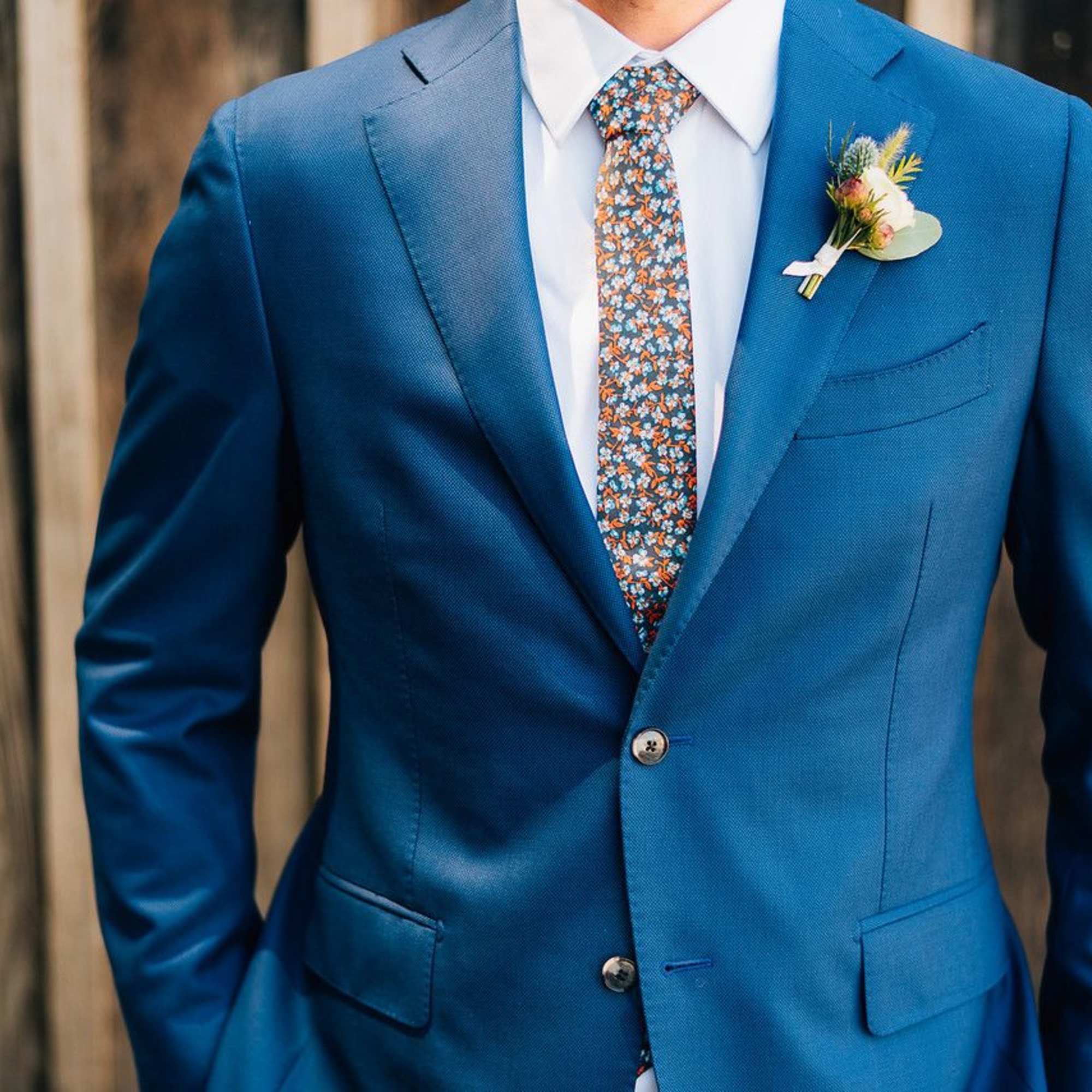 Man in a blue suit with a floral boutonniere on the lapel