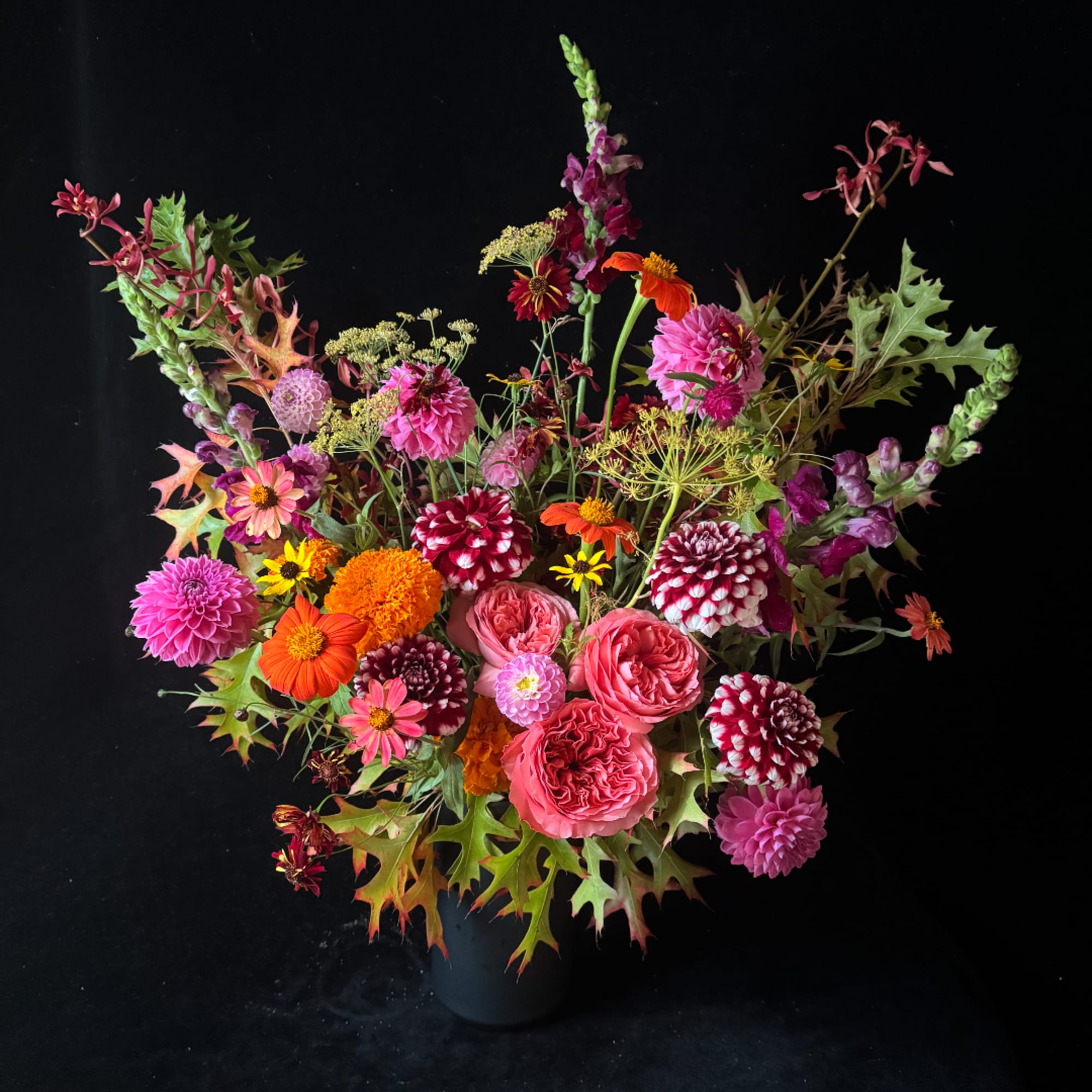 Colorful mixed bouquet in a dark vase with pink, orange, and burgundy blooms