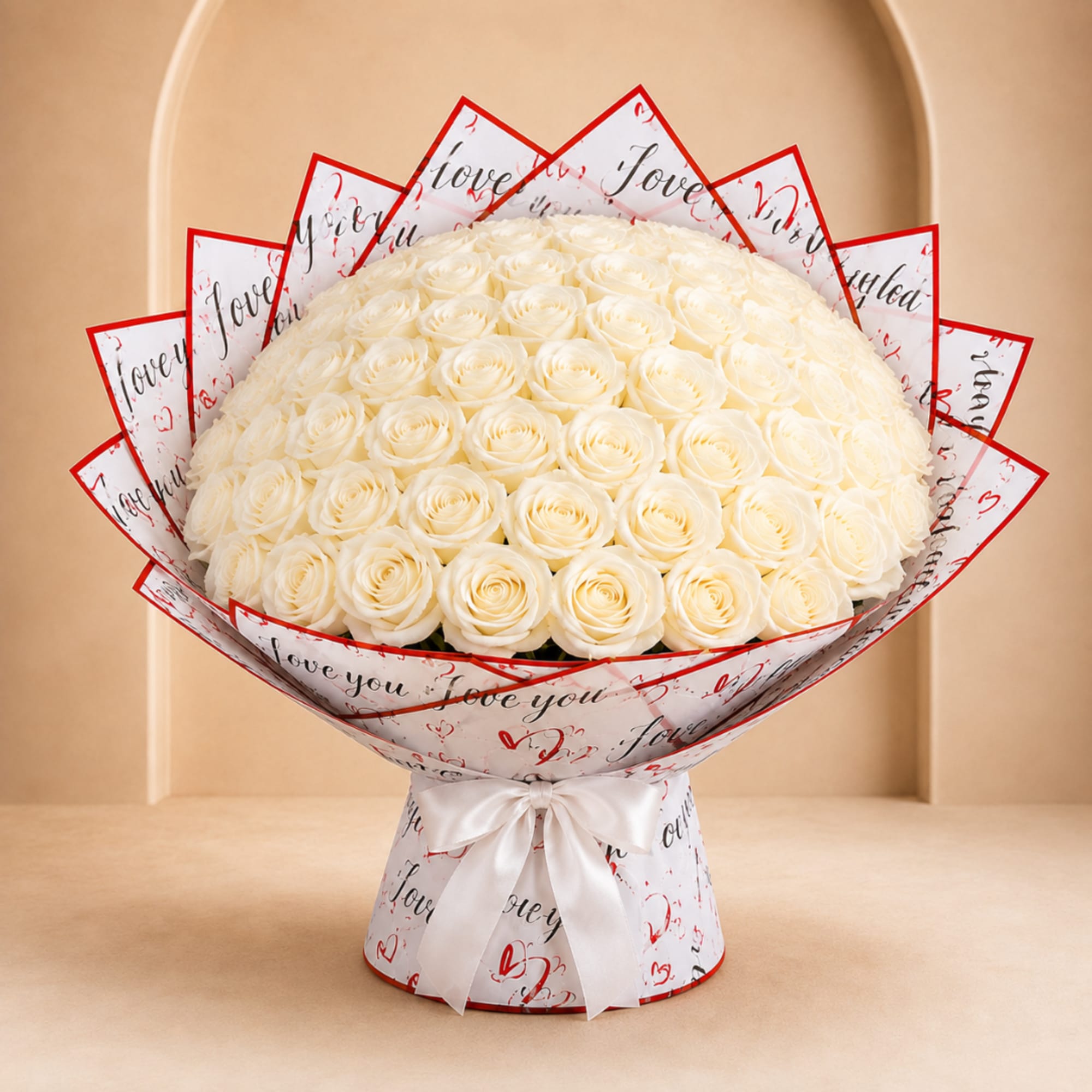 Large bouquet of white roses wrapped in printed paper with a white ribbon