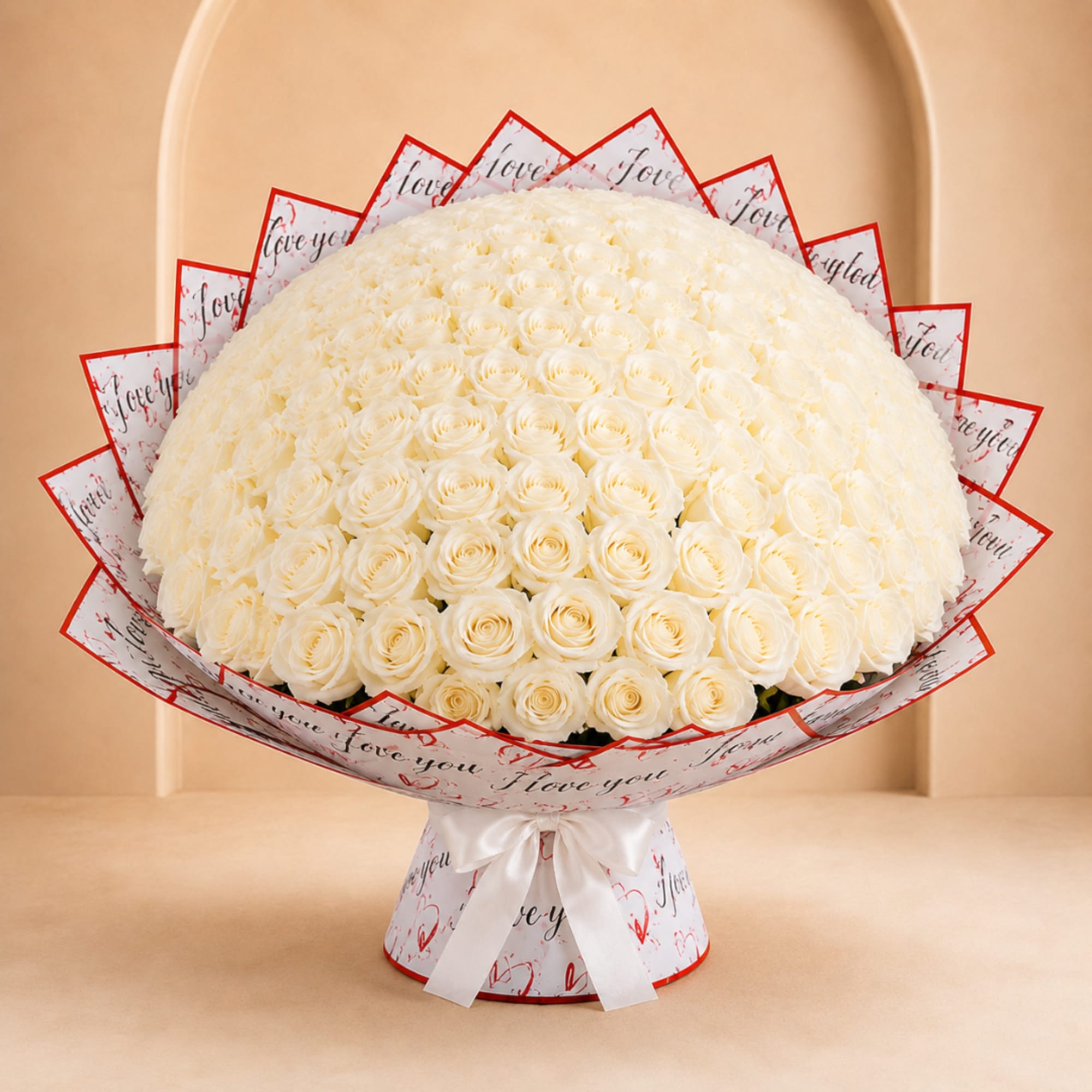 Large bouquet of white roses wrapped in printed paper with a white ribbon