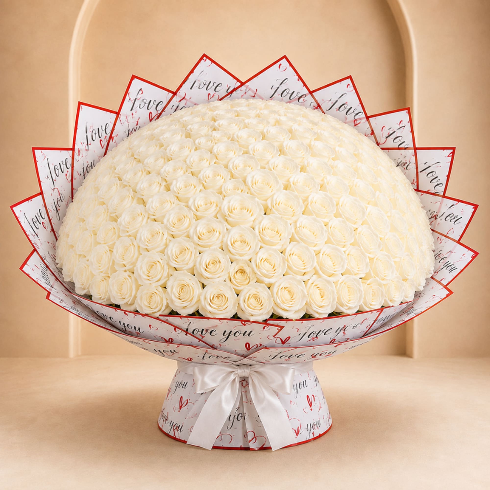 Large bouquet of white roses wrapped in printed paper with a white ribbon