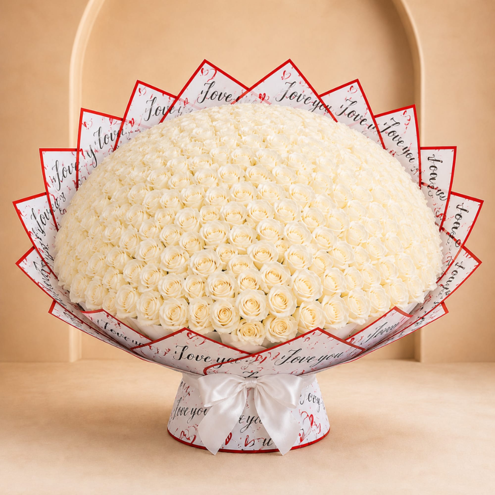 Large bouquet of white roses wrapped in printed paper with a white ribbon