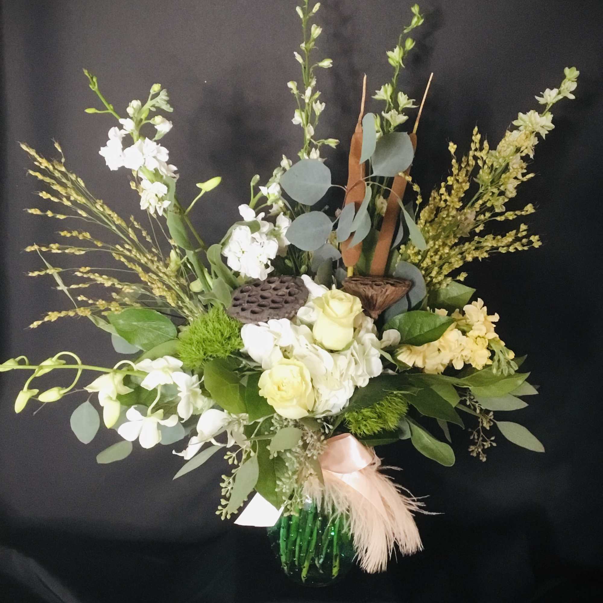 White and pale yellow floral arrangement in a green glass vase