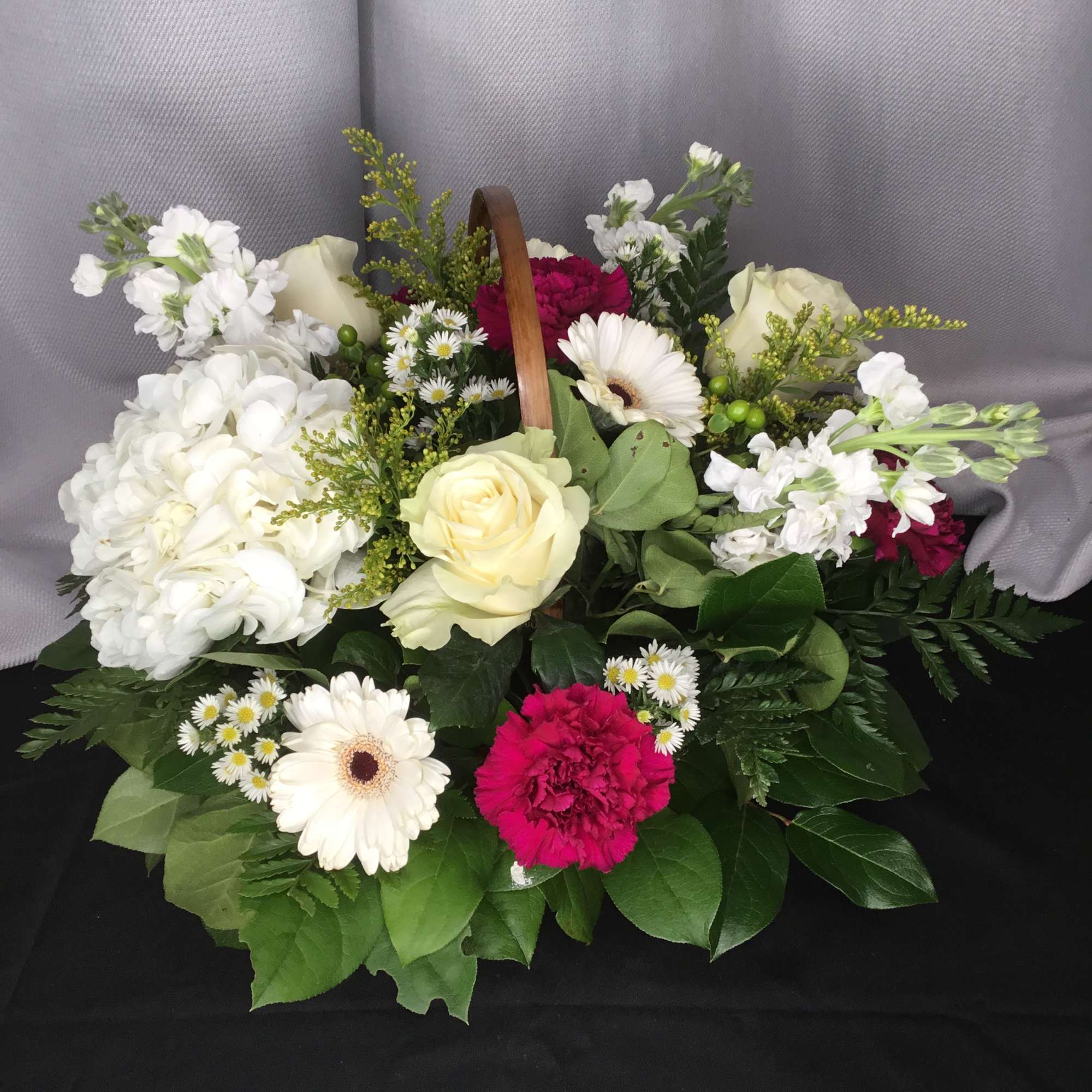 Basket arrangement of white and pink flowers with a wooden handle