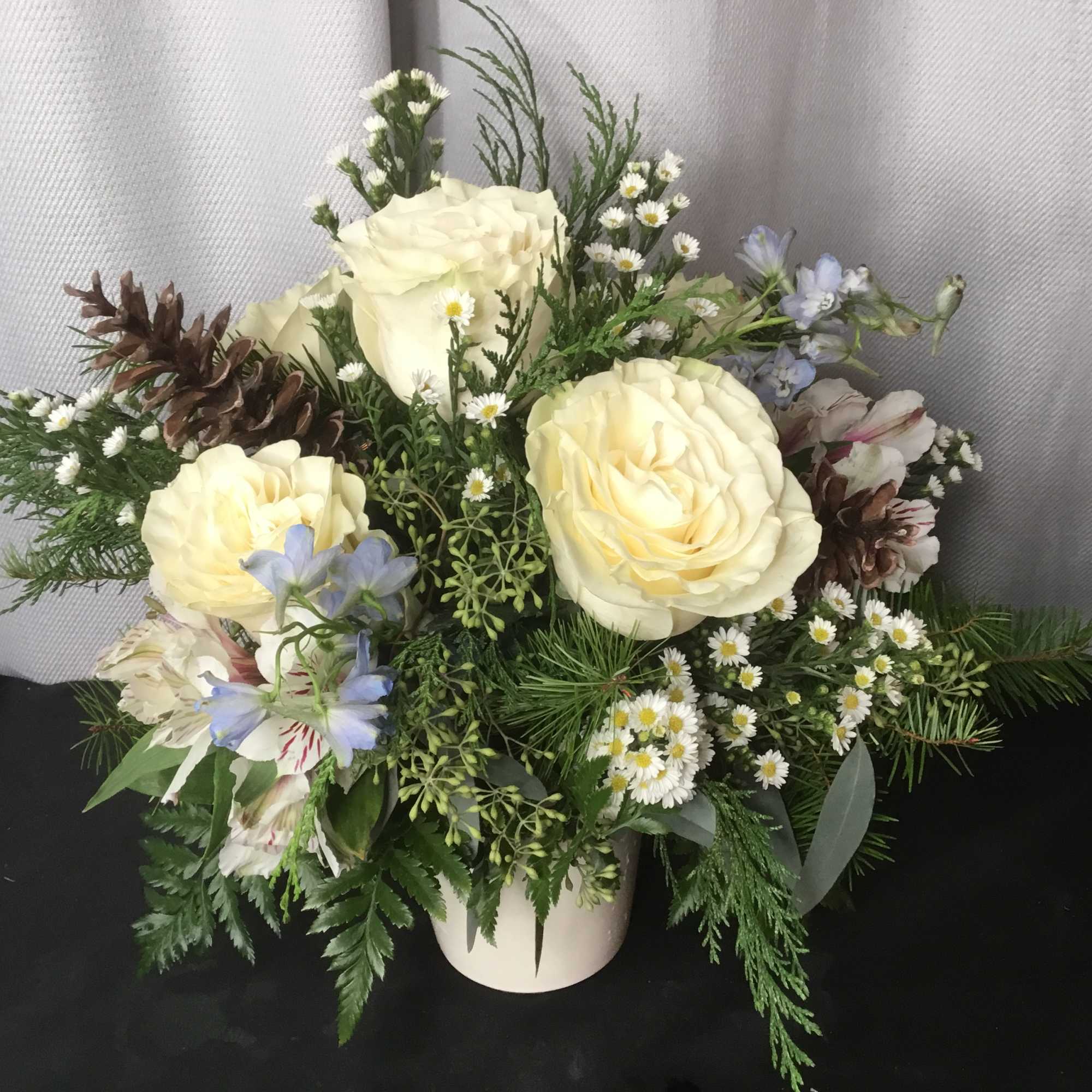 Cream roses in a white vase with small daisy-like flowers and greenery