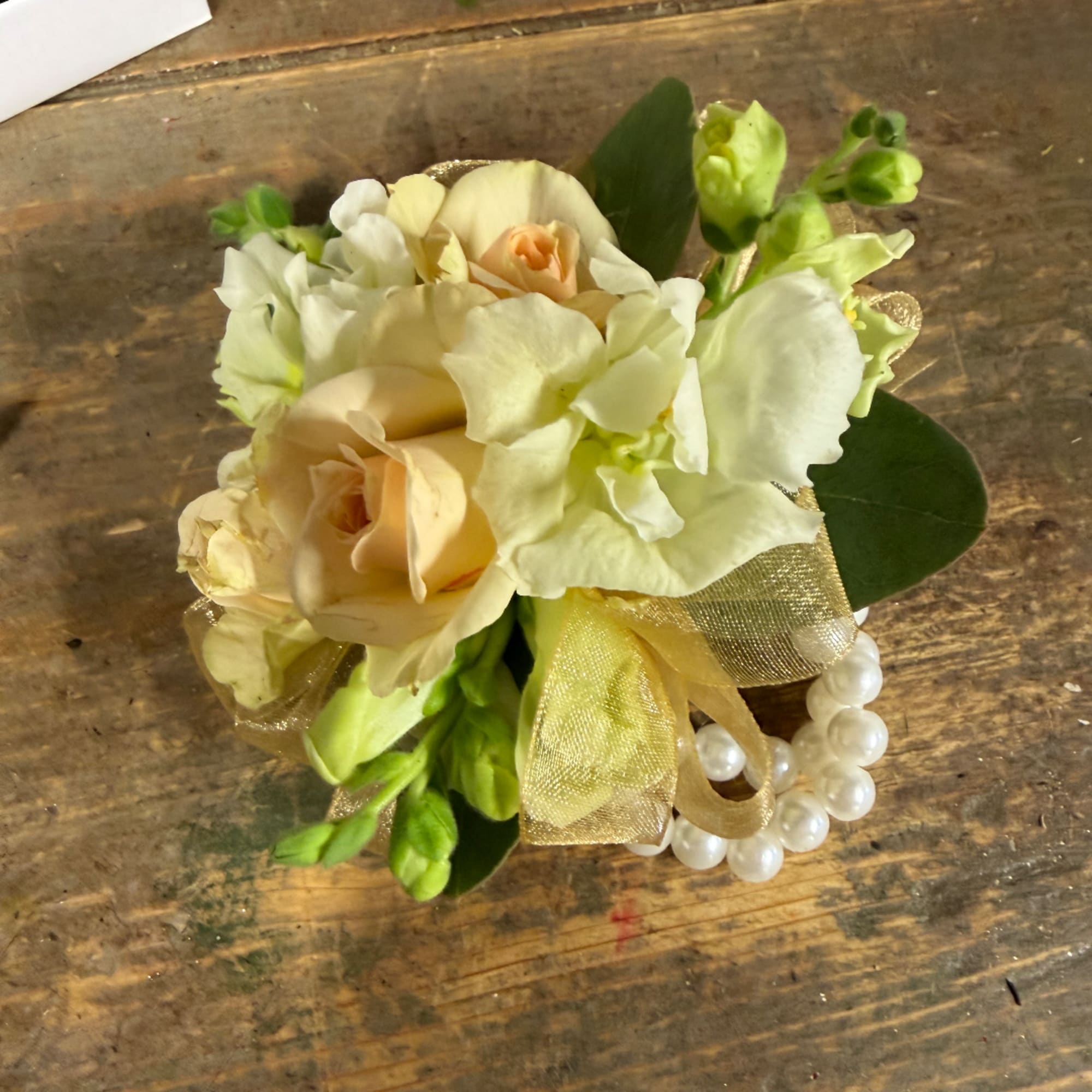 Small cream and peach floral arrangement with ribbon and pearl accents
