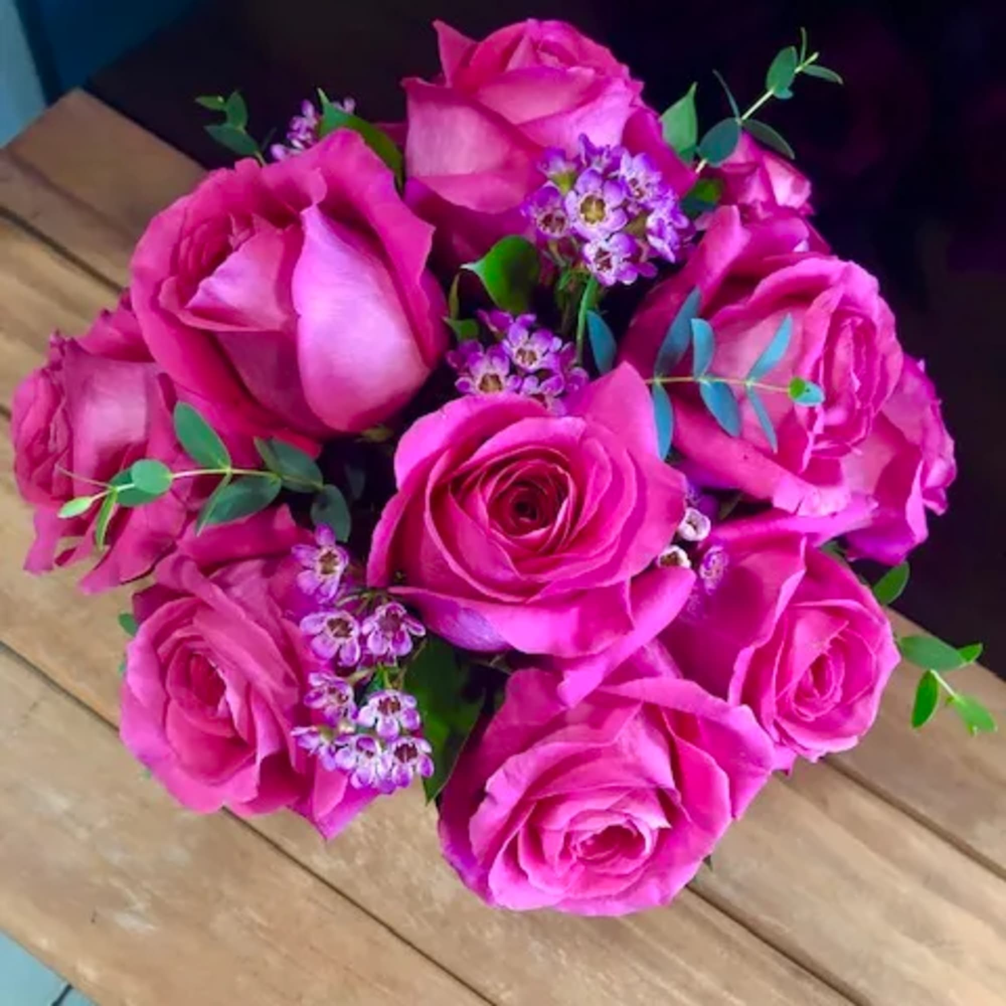 Tight bouquet of hot pink roses with small purple filler flowers viewed from above