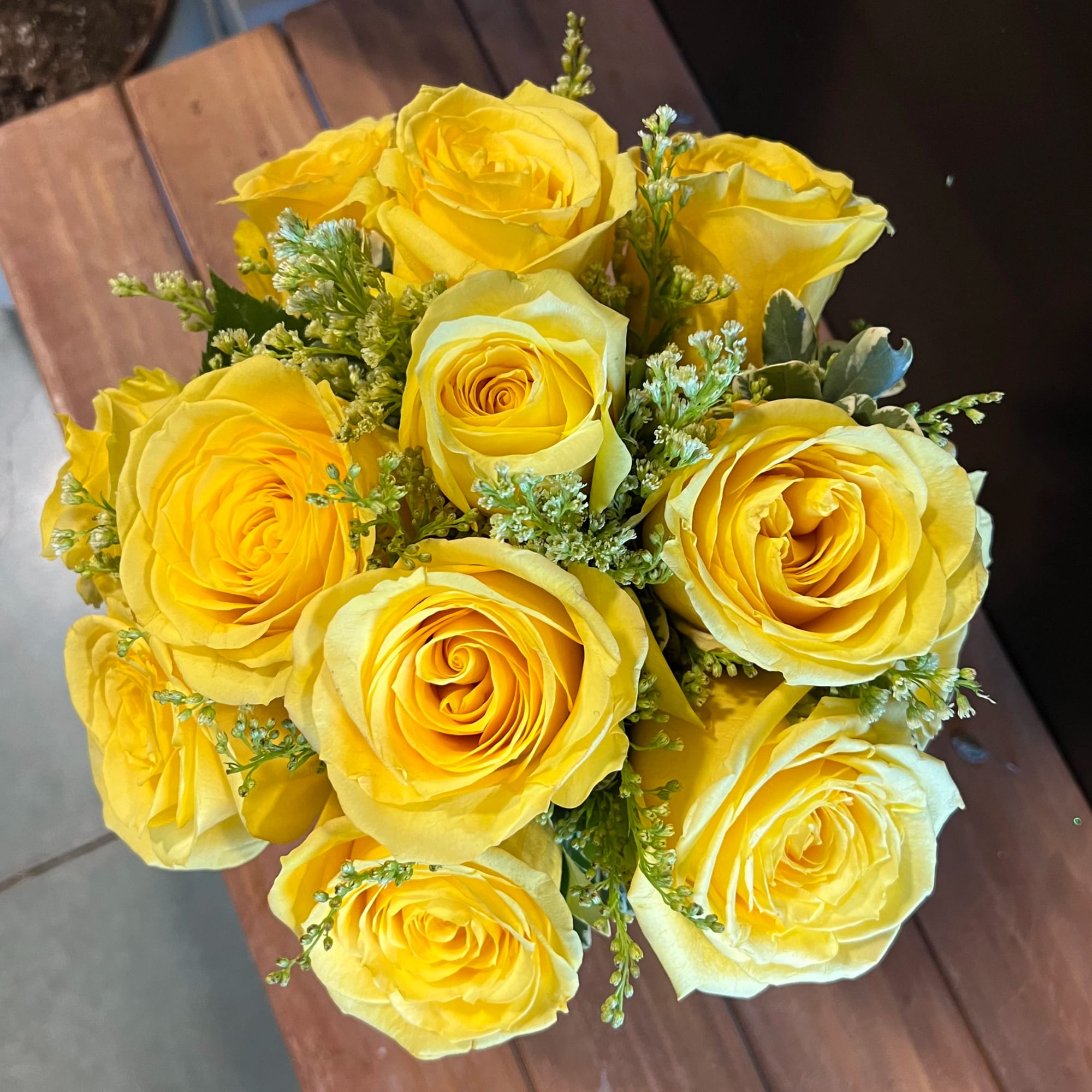 Tight bouquet of bright yellow roses arranged in a round cluster.