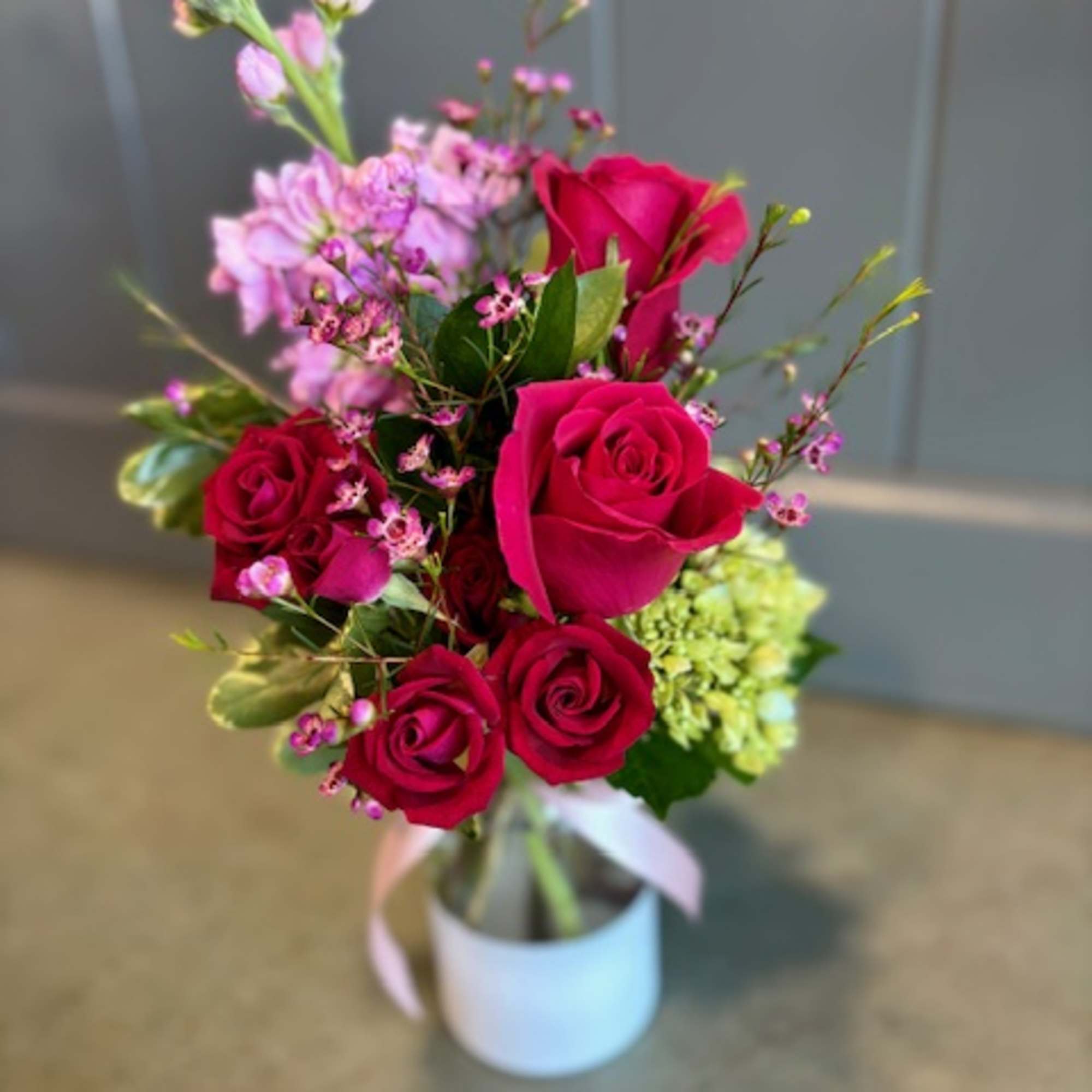 Bouquet of red roses and pink flowers in a white vase
