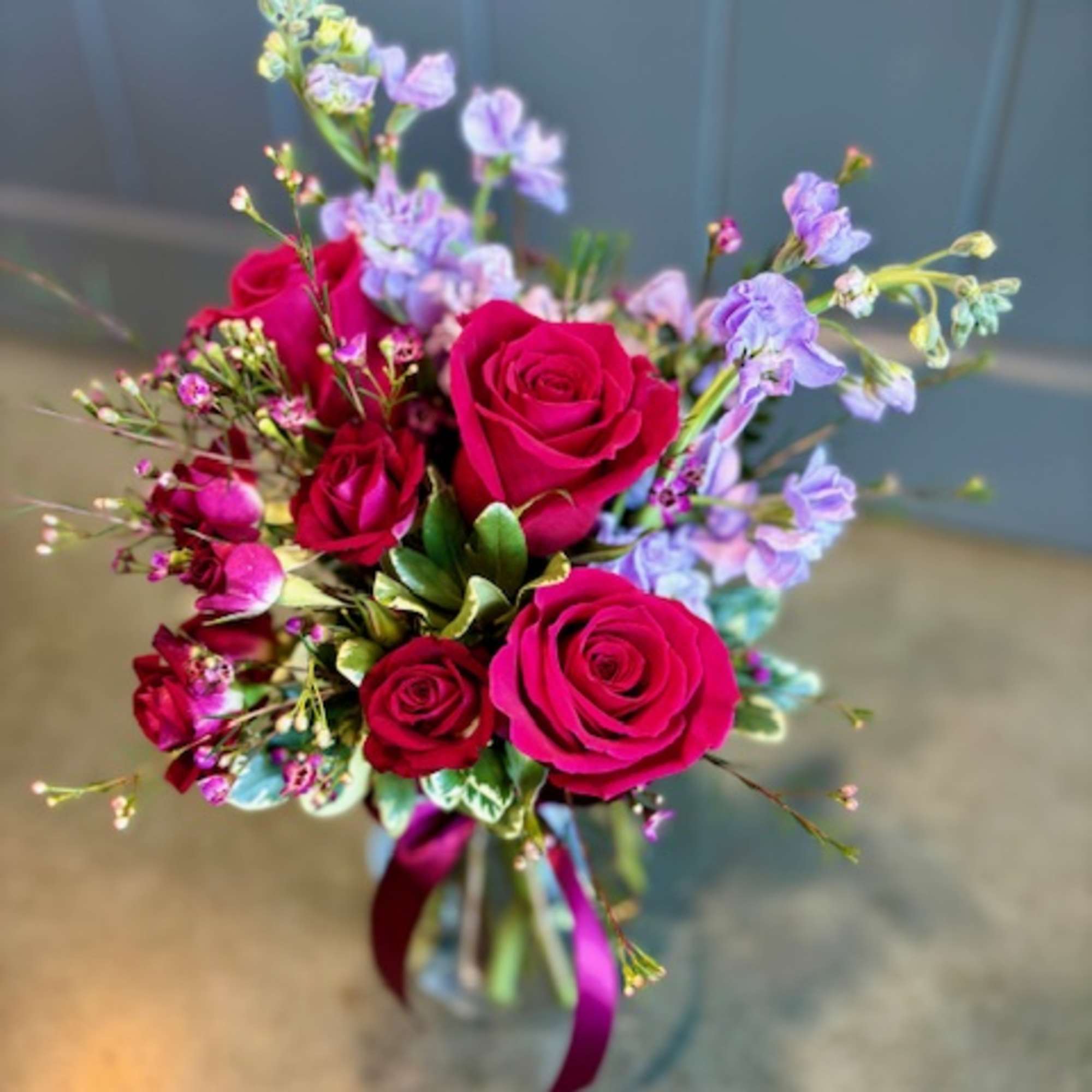 Bouquet of red roses and lavender flowers tied with ribbon