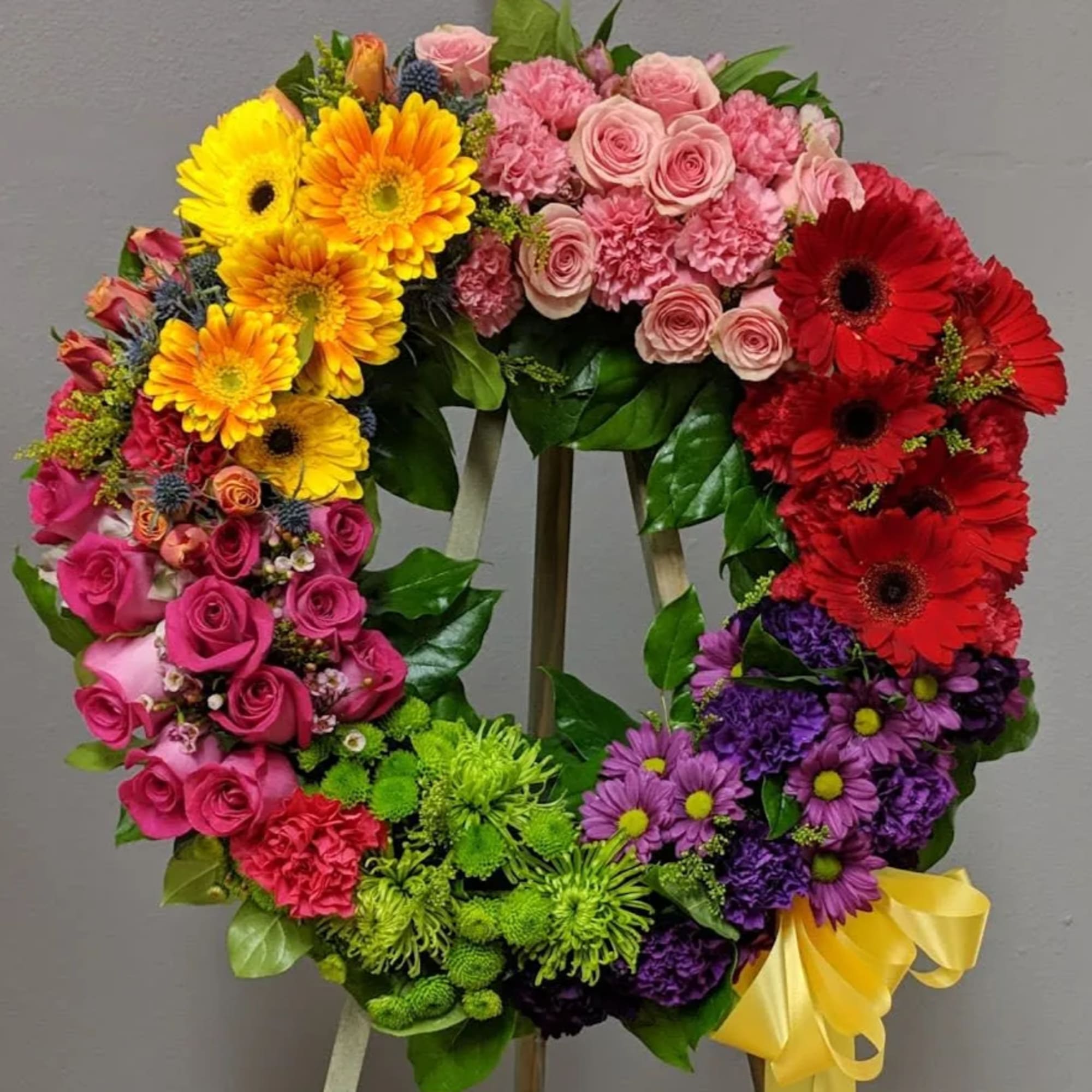 Colorful floral wreath with roses, gerbera daisies, and chrysanthemums on an easel