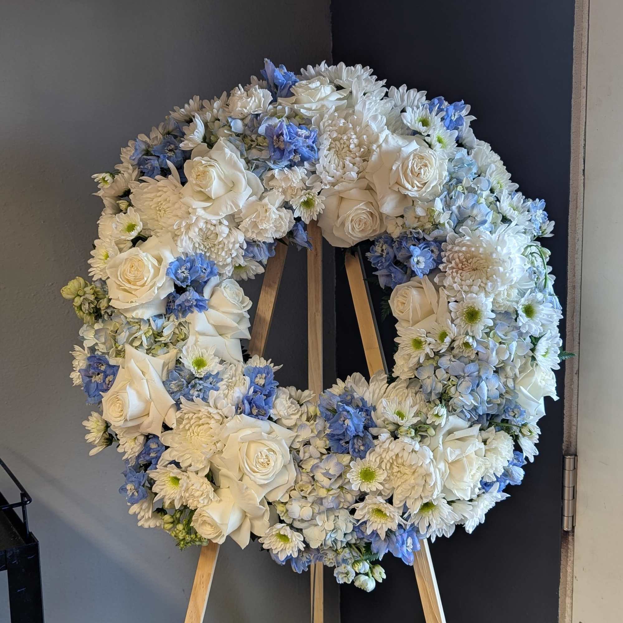 White and blue floral wreath on a wooden easel