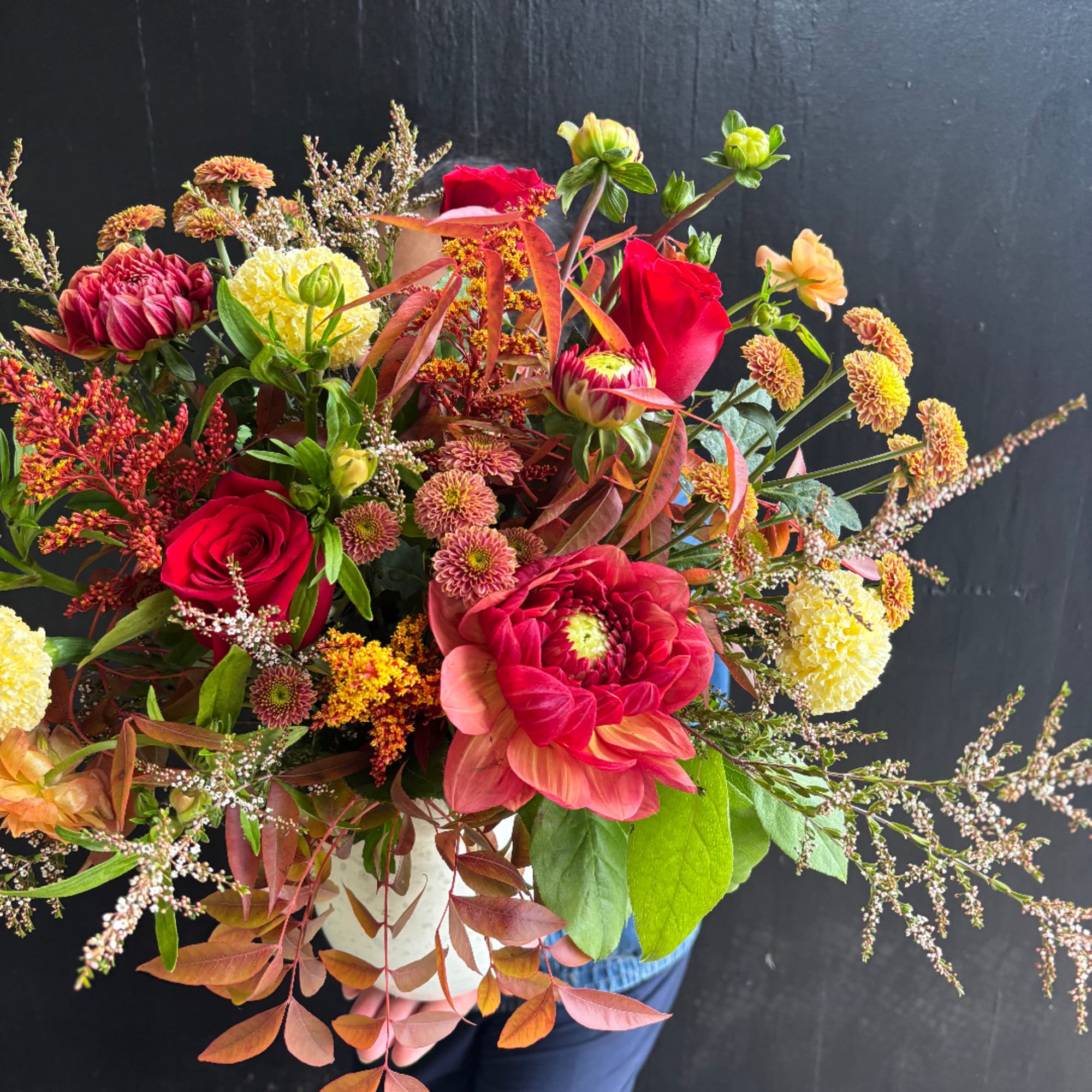 Mixed bouquet of red, pink, and yellow flowers in a white vase