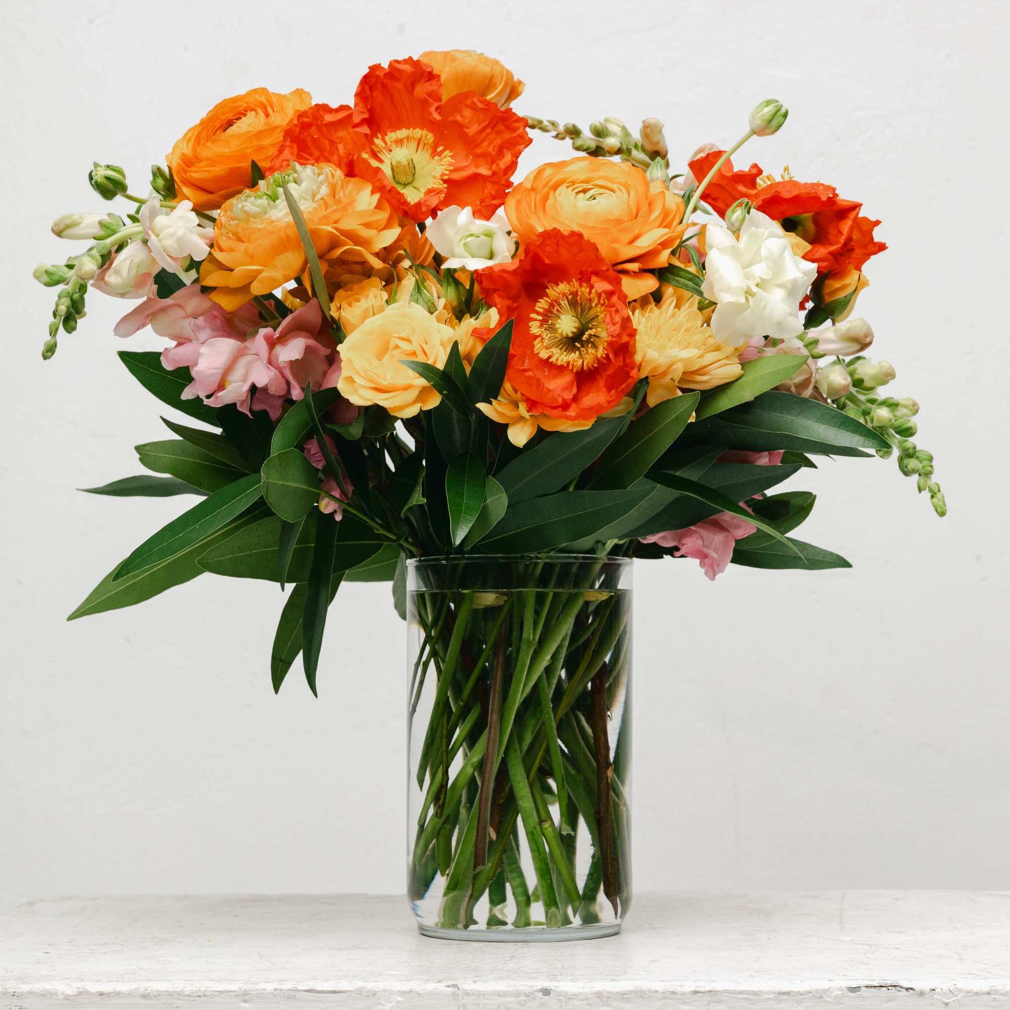 Orange and pink mixed bouquet in a clear glass vase