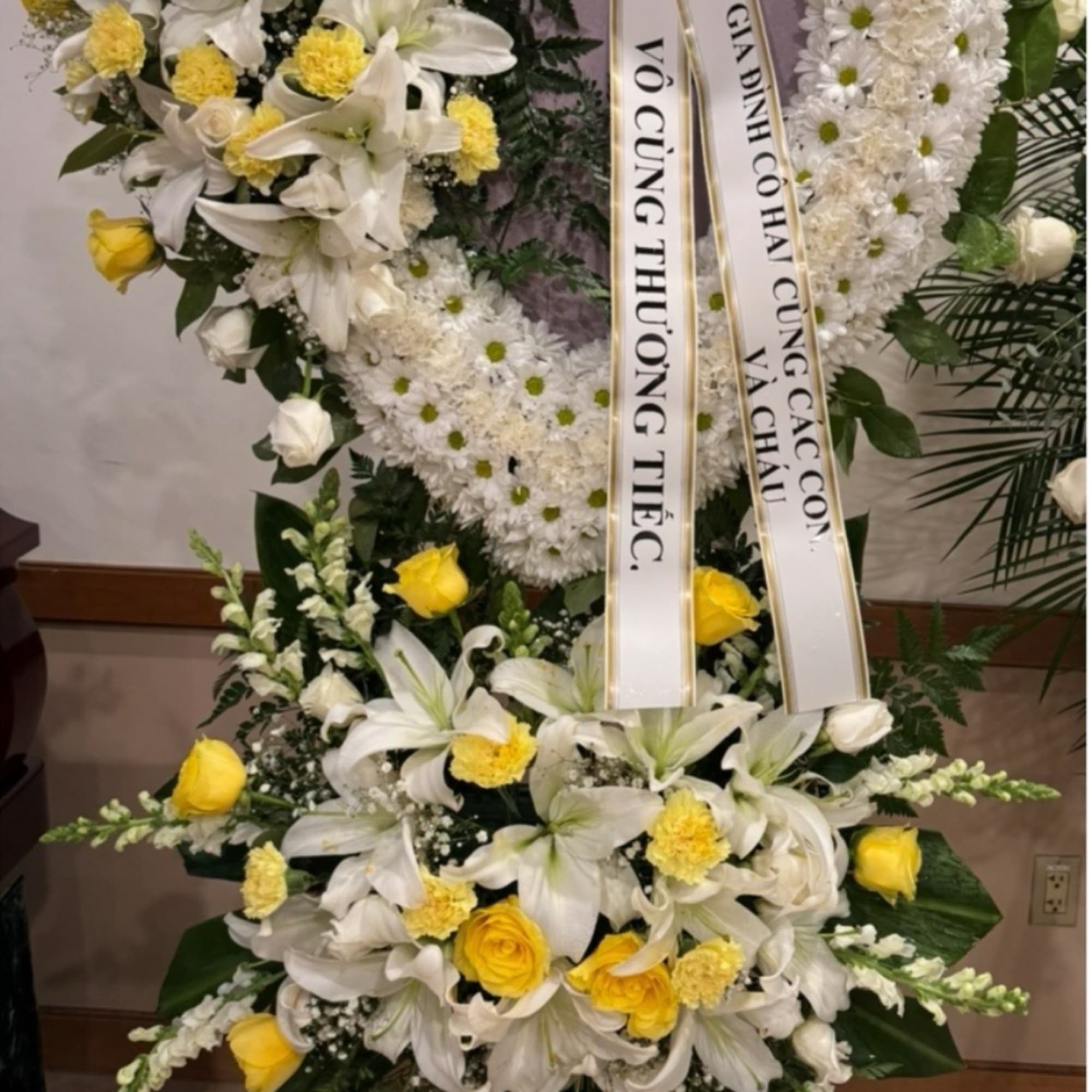 Tall white and yellow condolence standing spray with ribbons