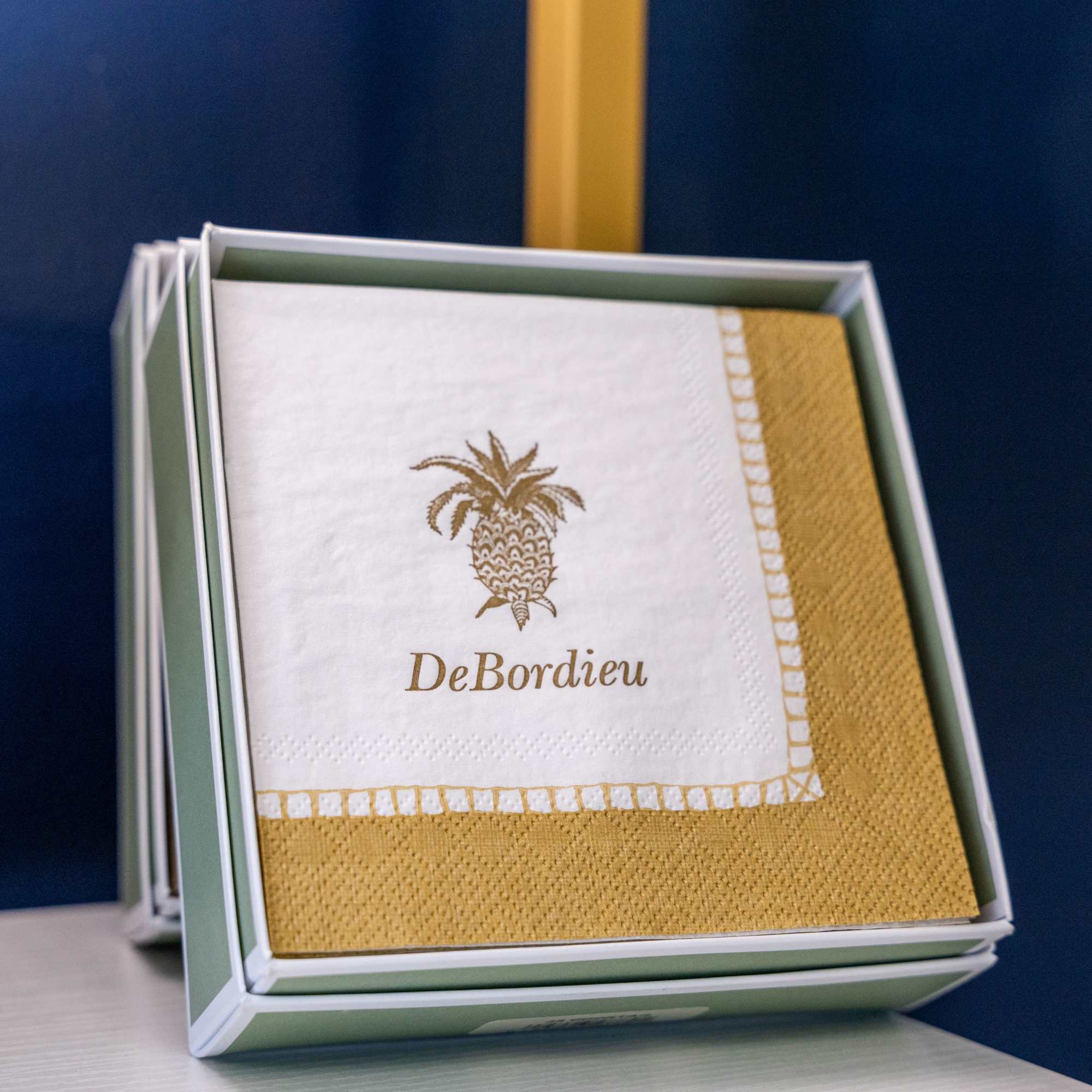 Boxed napkins with a gold pineapple design and DeBordieu text