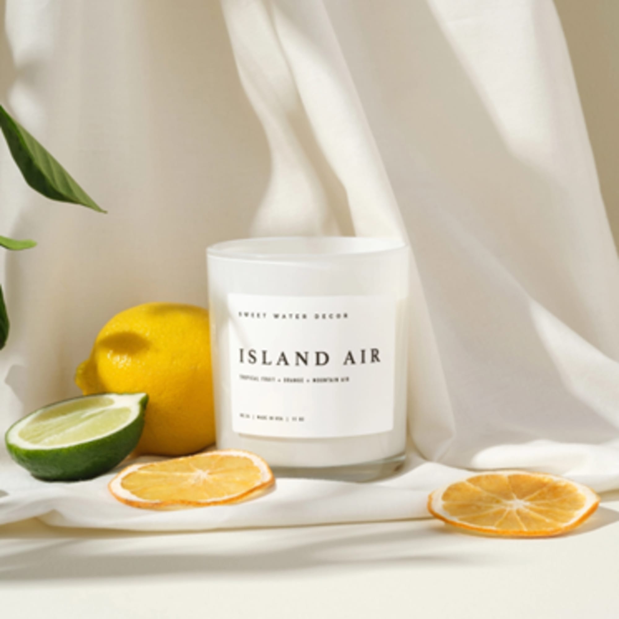 Citrus-scented candle in a glass jar with lemon and lime slices