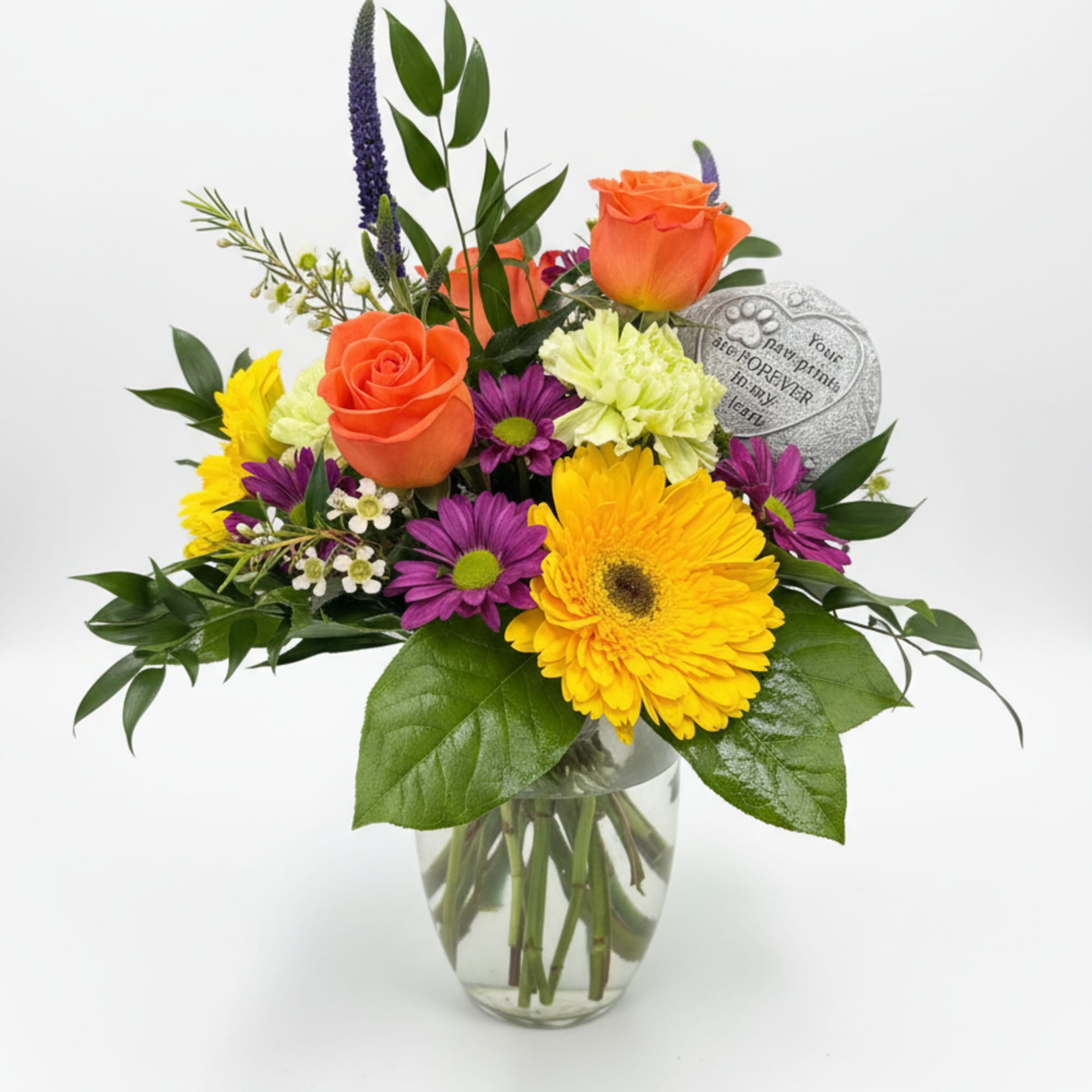 Mixed bouquet with orange roses, yellow gerbera daisies, and purple flowers in a glass vase