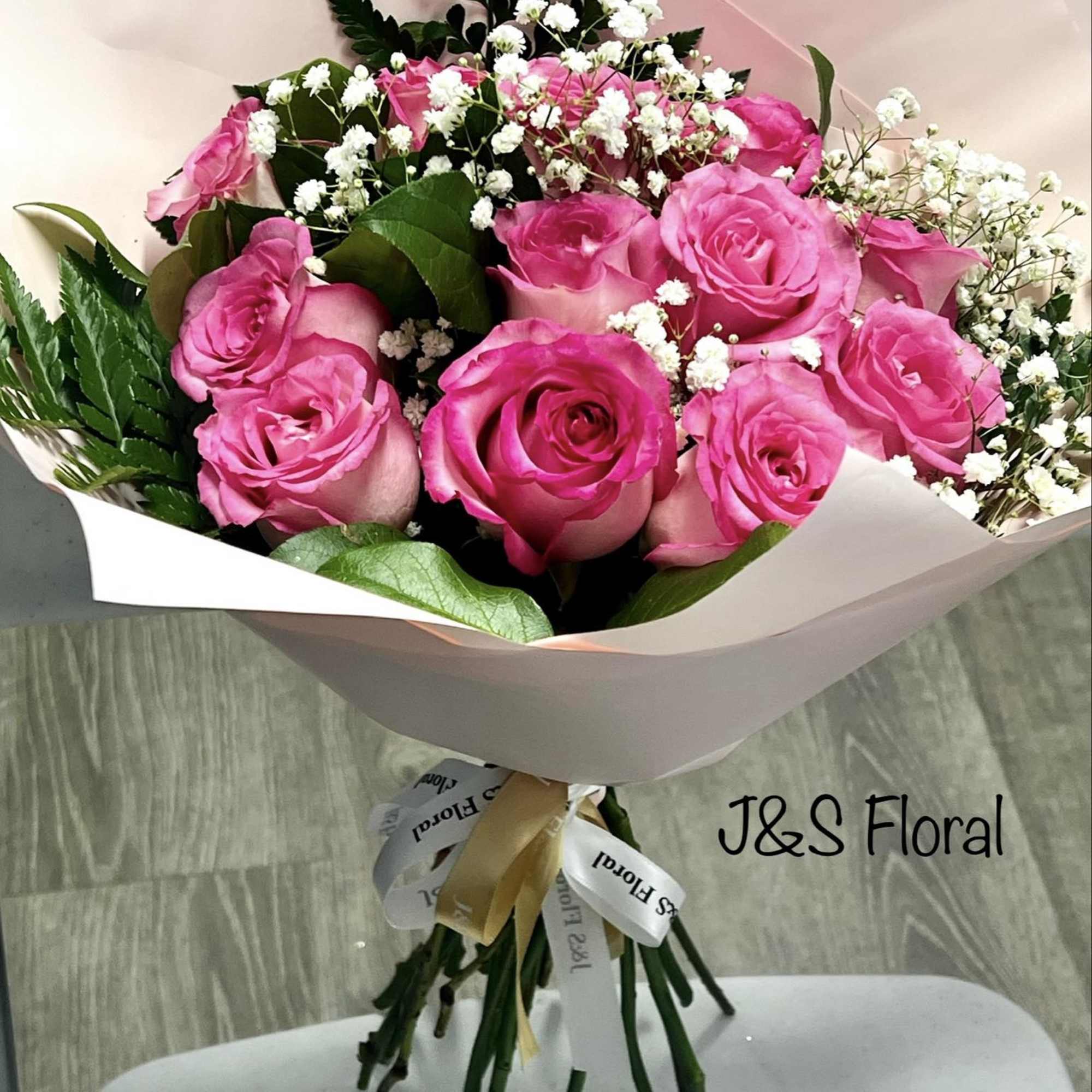 Bouquet of pink roses with baby's breath wrapped in pale paper