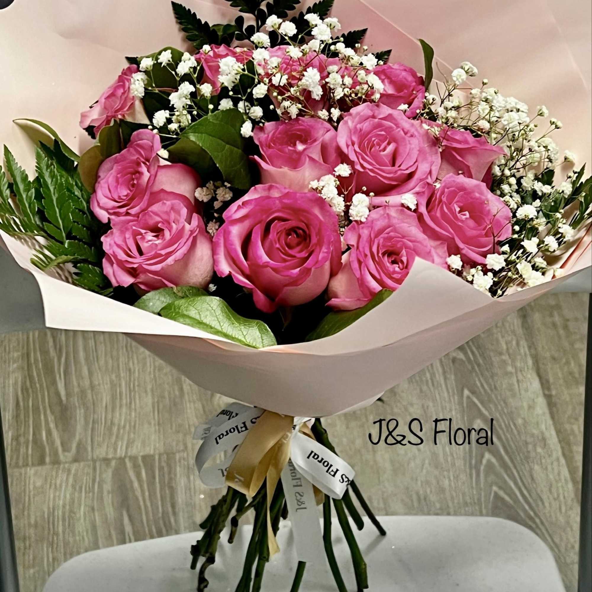 Bouquet of pink roses with white baby's breath in pale wrapping