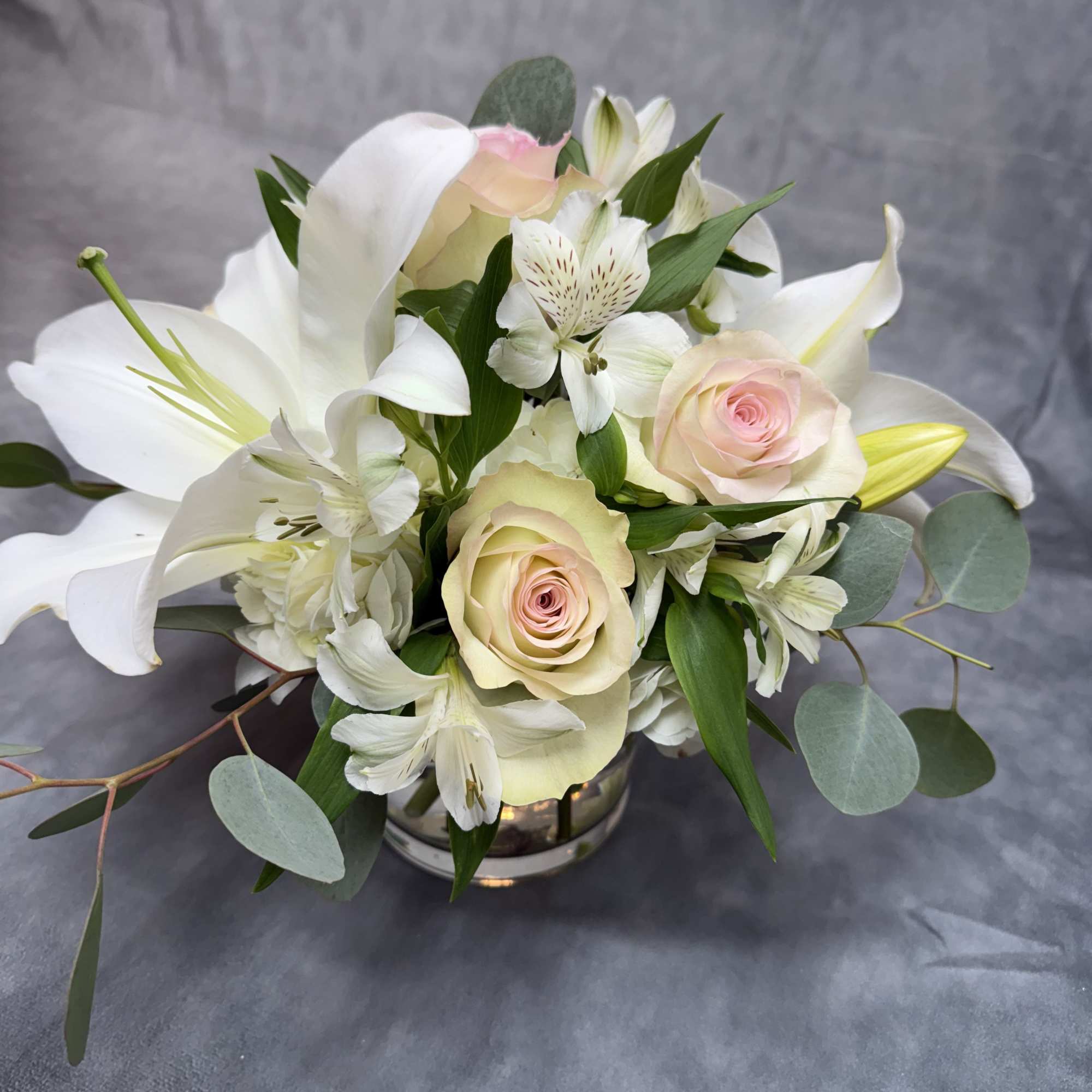 White lilies and pale pink roses in a low vase arrangement