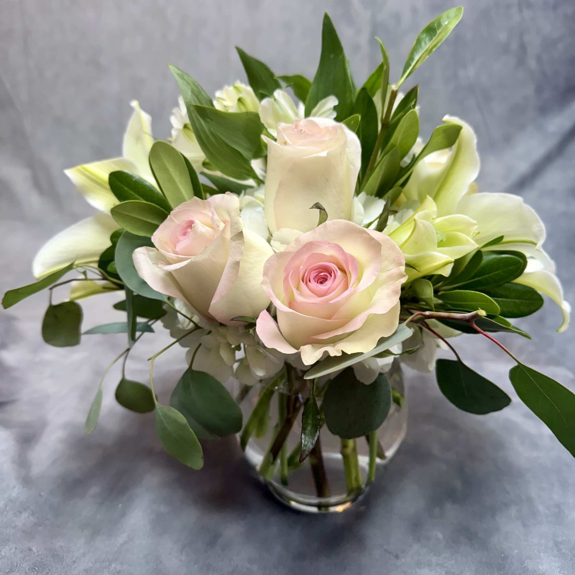 Pink roses and white lilies arranged in a clear glass vase