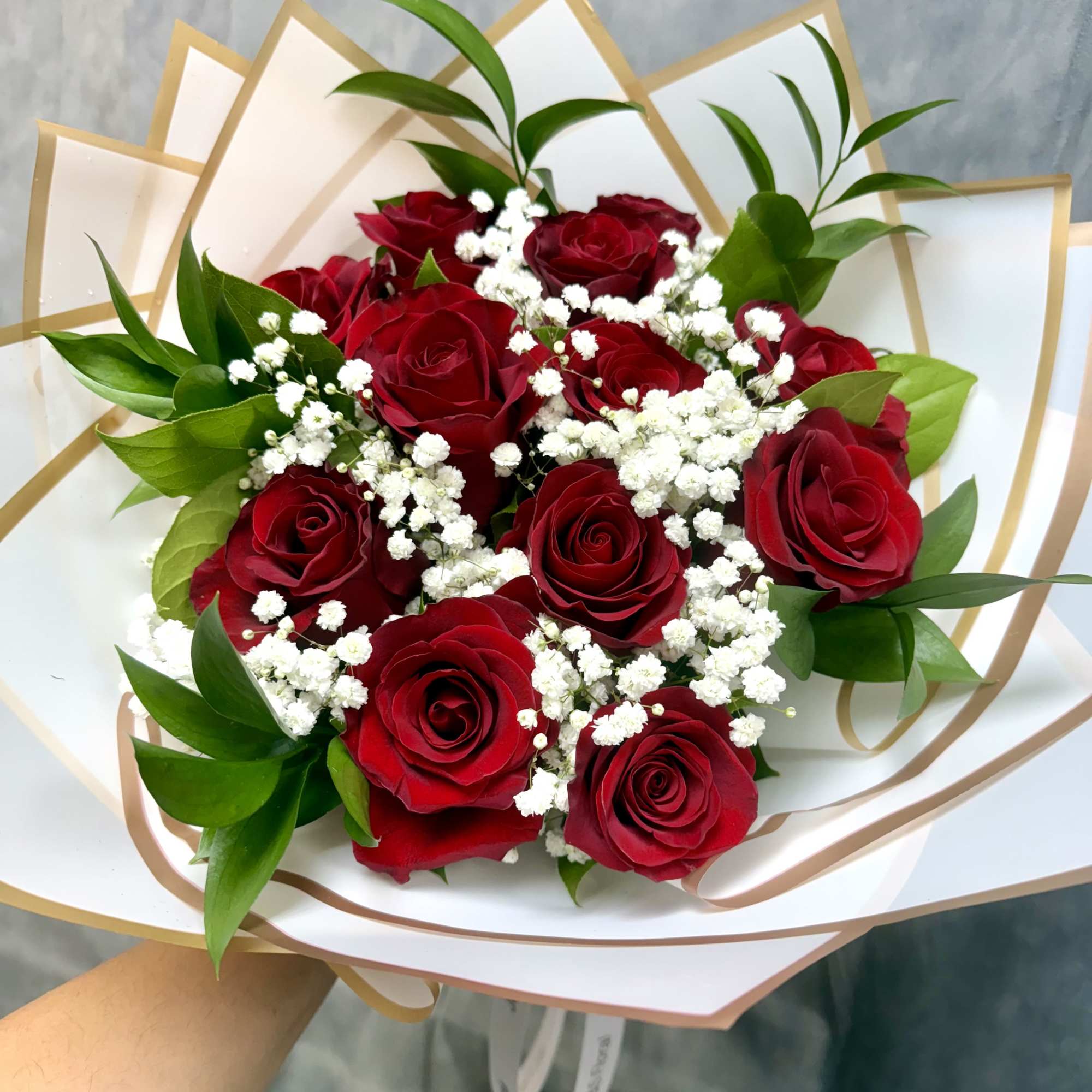Bouquet of red roses with white baby's breath in white and gold wrap