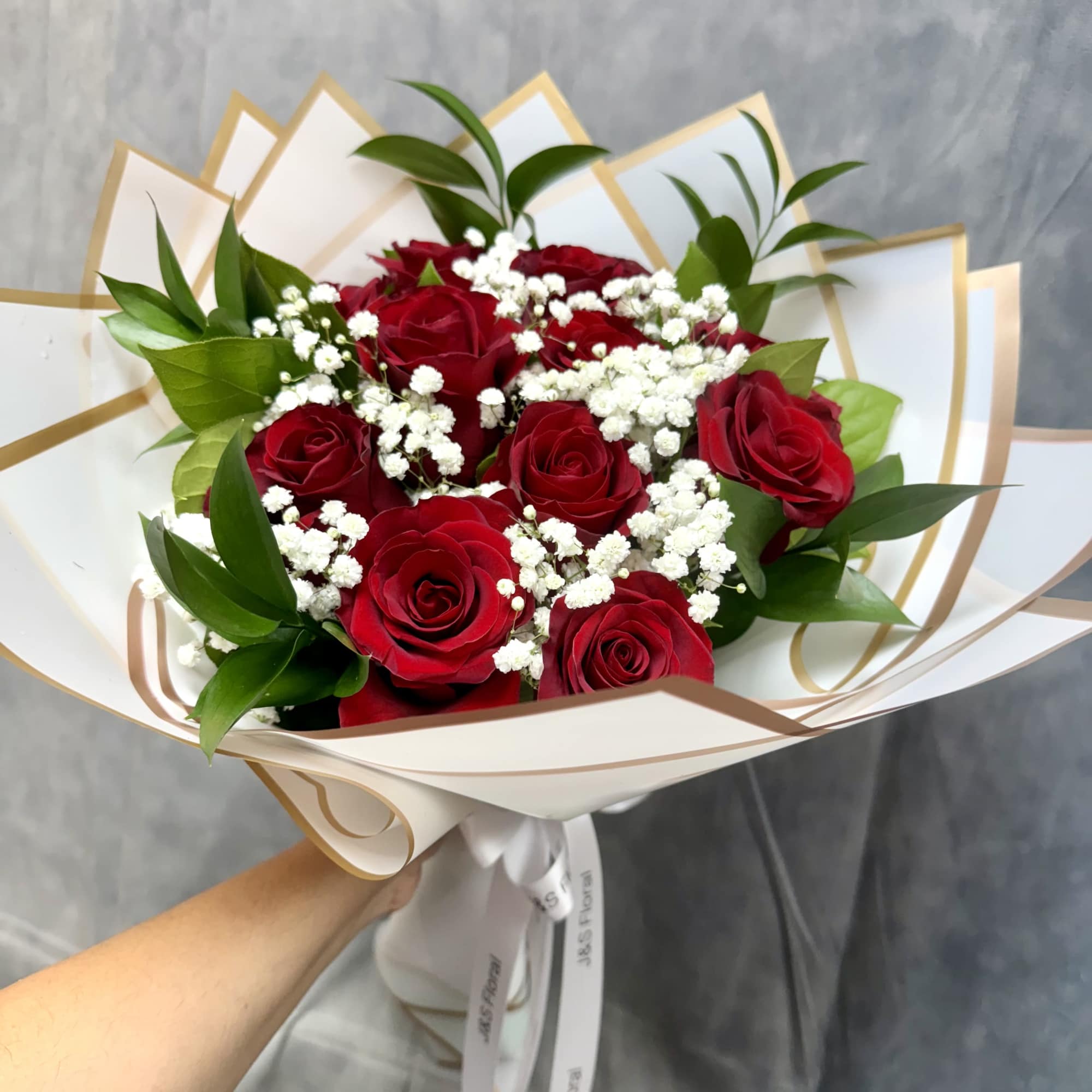 Bouquet of red roses with white baby's breath in white wrap