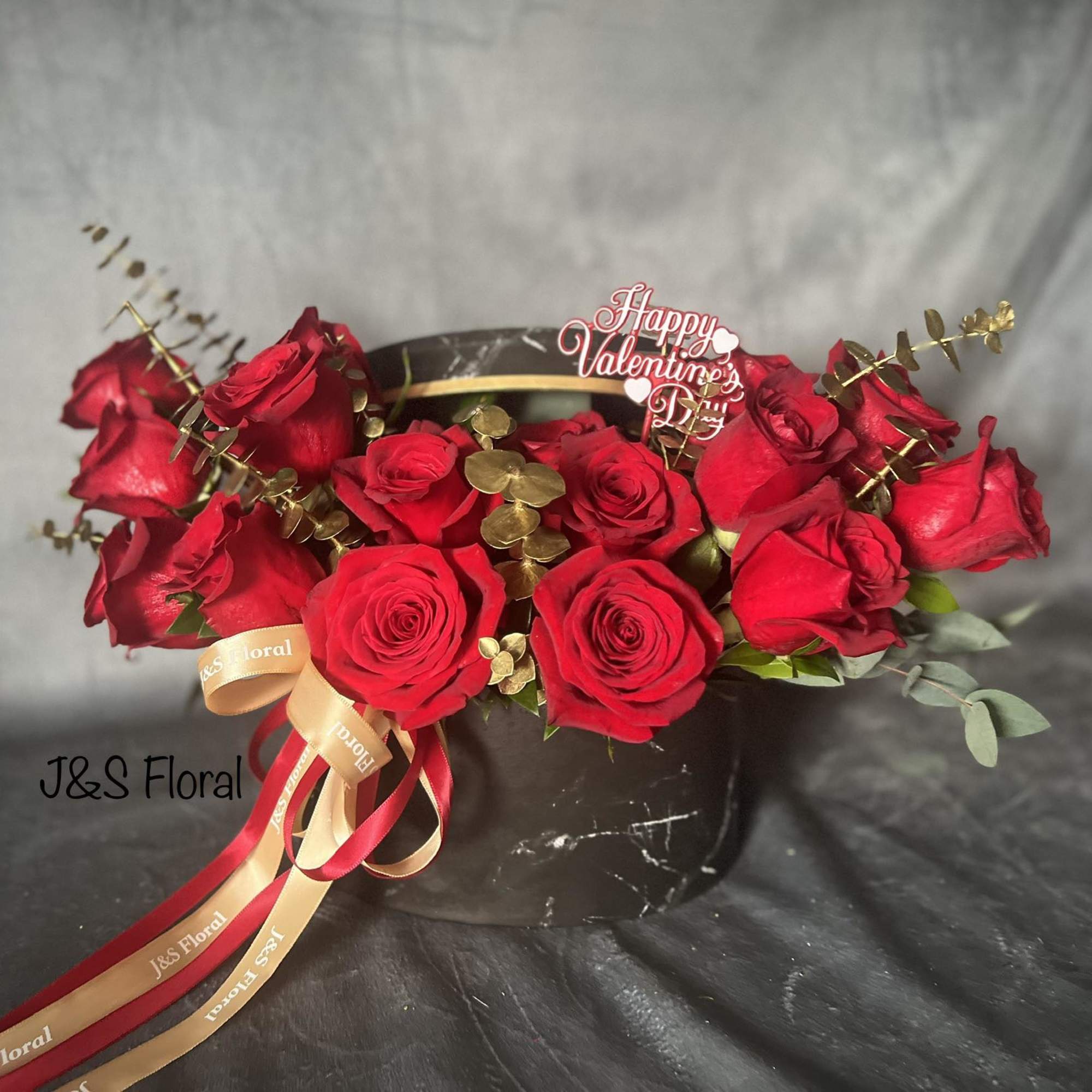Red roses arranged in a black hat box with a Valentine topper