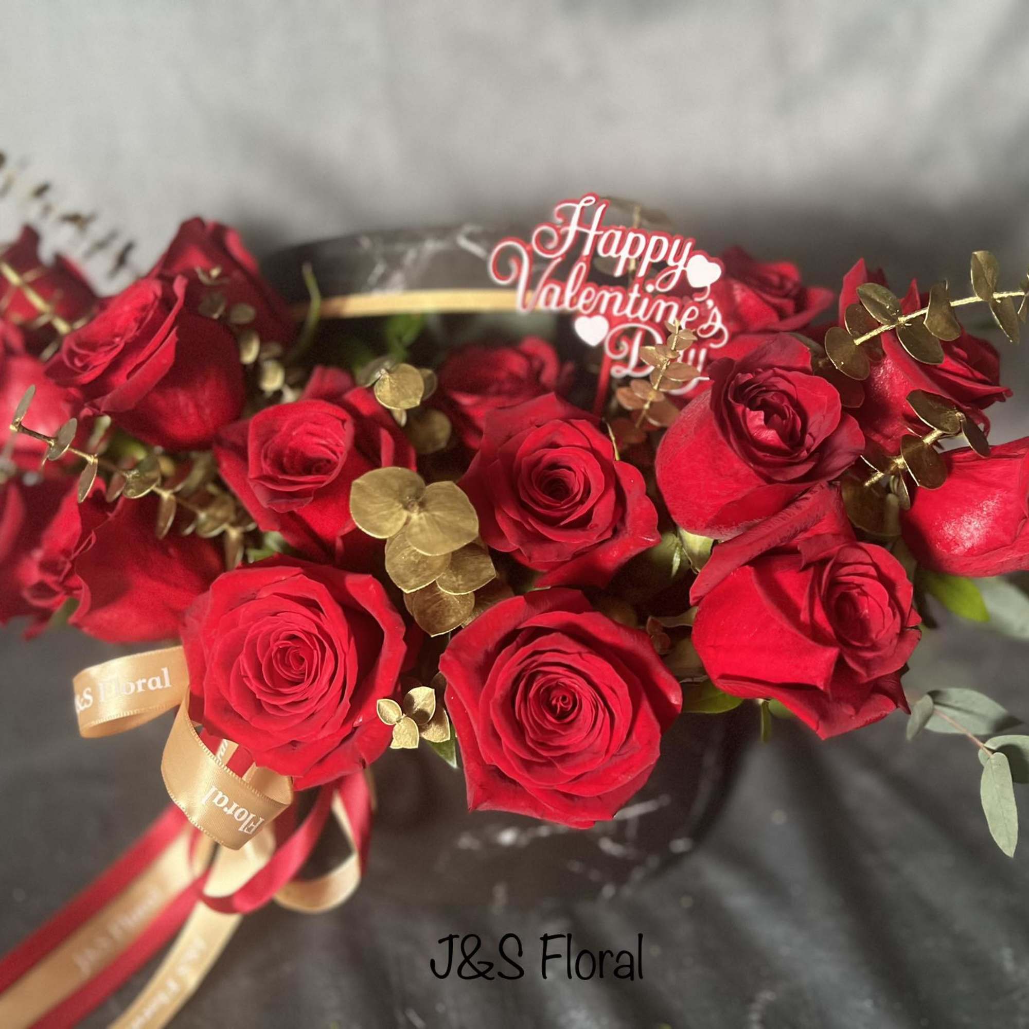 Bouquet of red roses with gold accents and a Valentine topper