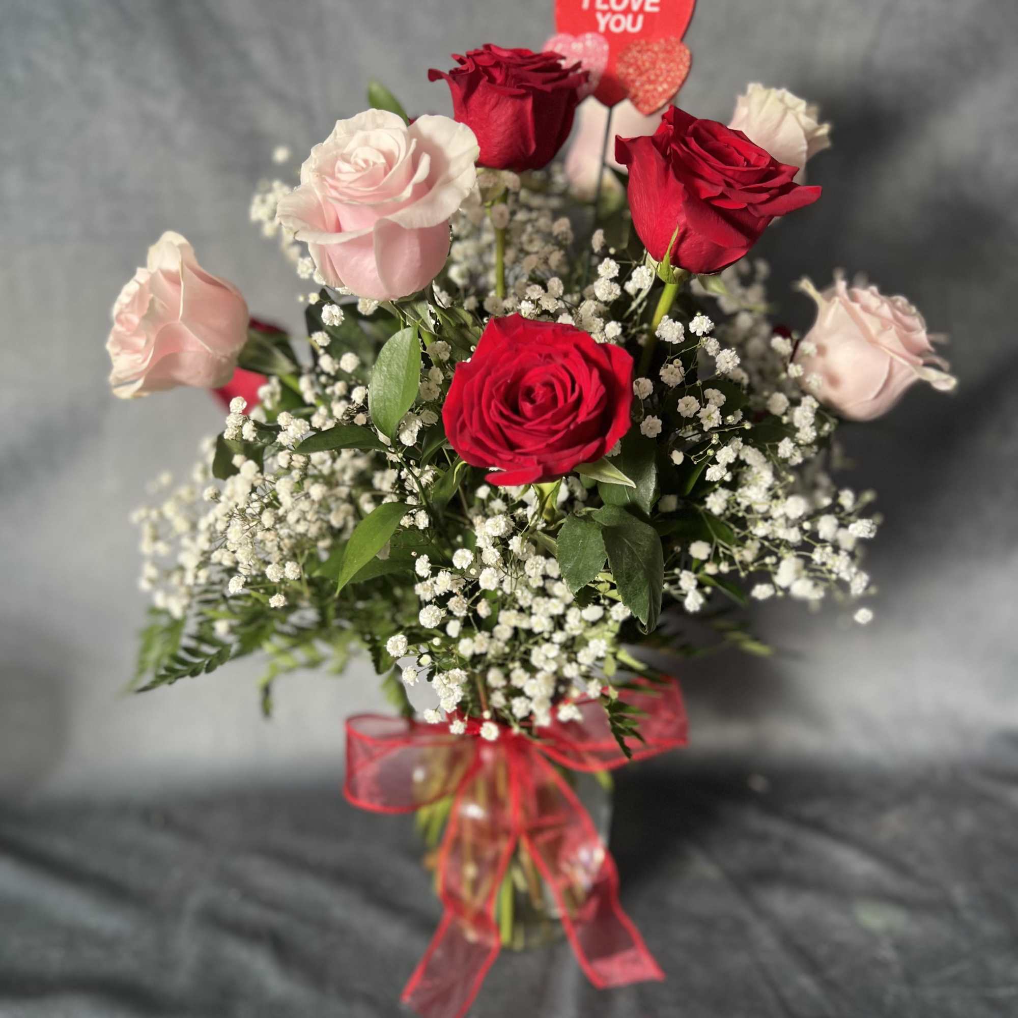 Bouquet of red and pale pink roses with a heart topper and red ribbon