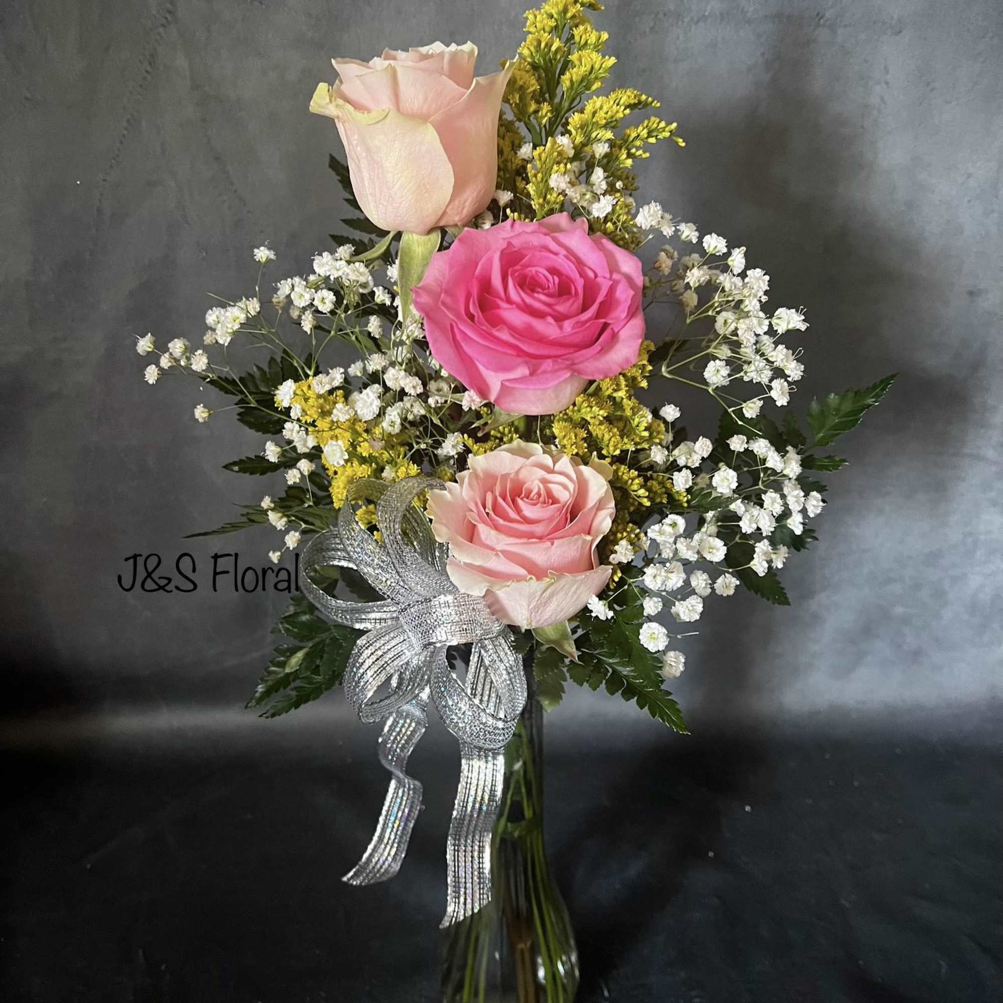 Pink and blush roses arranged in a glass vase with white filler flowers