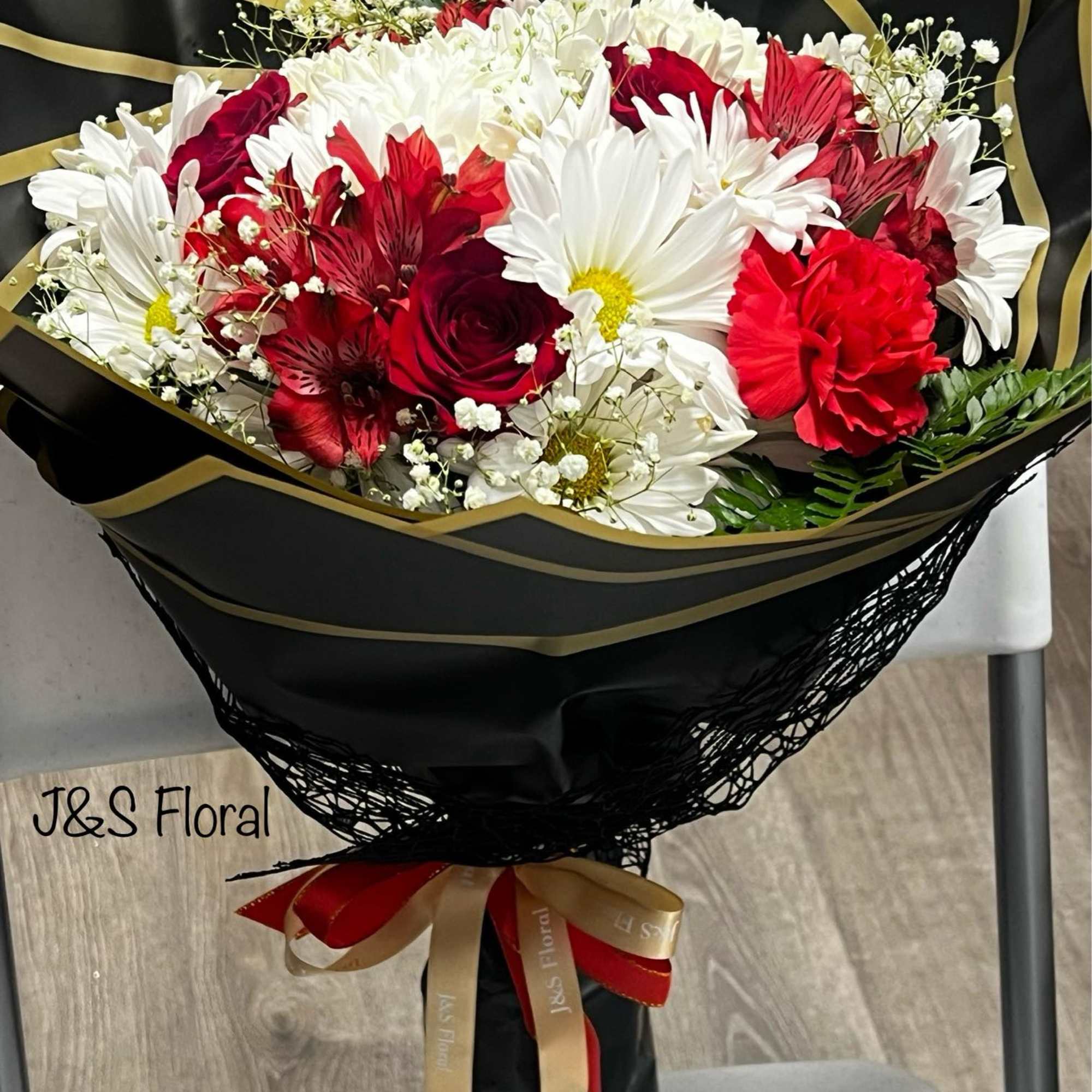 Bouquet of red and white flowers wrapped in black paper