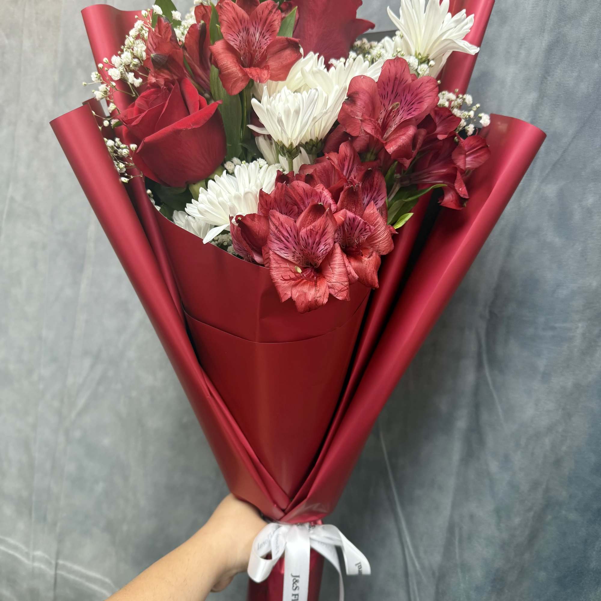 Red and white bouquet with roses, daisies, and alstroemeria in red wrap