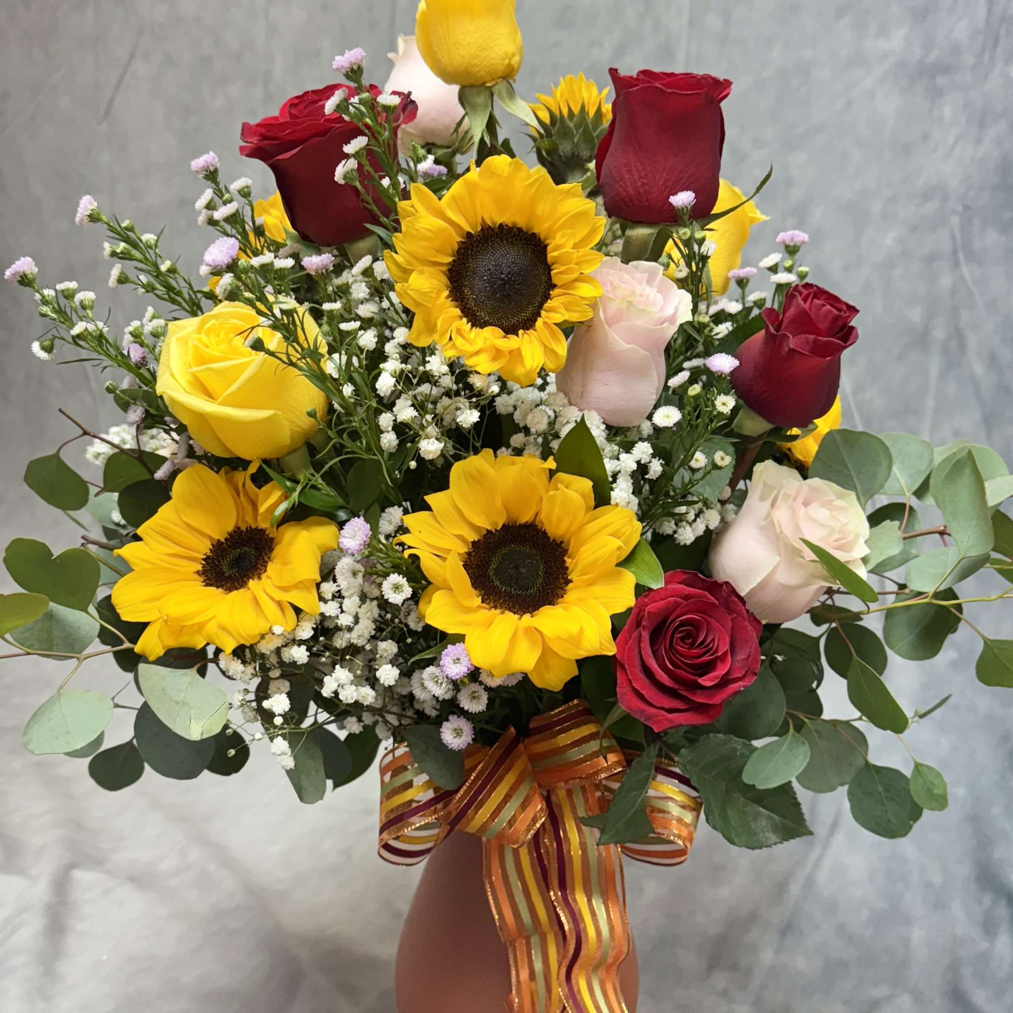 Bouquet of red and yellow roses with sunflowers in a vase