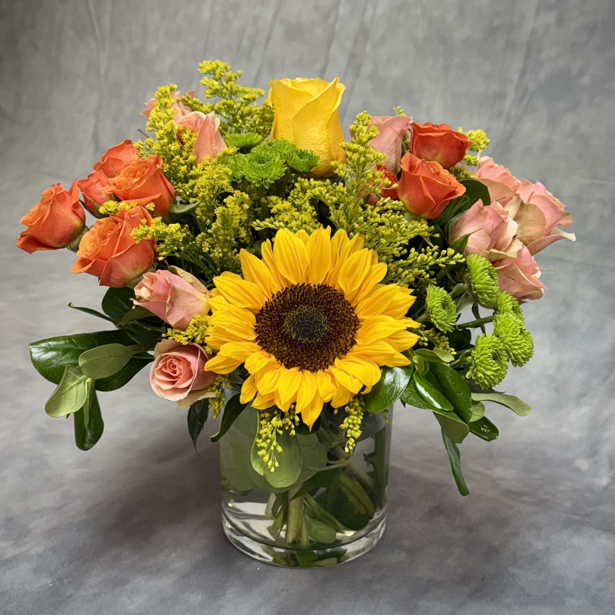 Bouquet of sunflowers and roses in a clear glass vase
