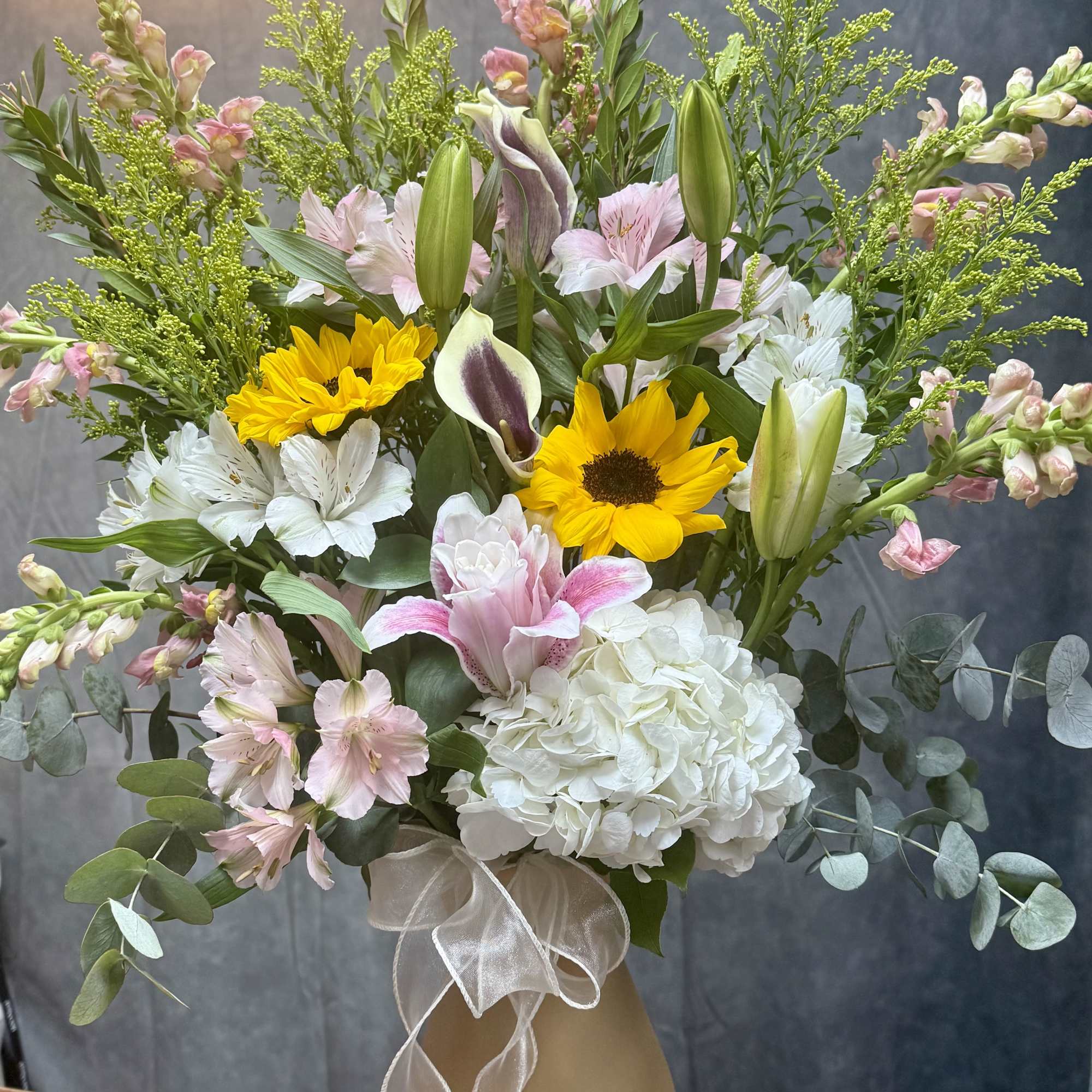 Mixed bouquet with sunflowers, lilies, hydrangea, and pink alstroemeria in a vase
