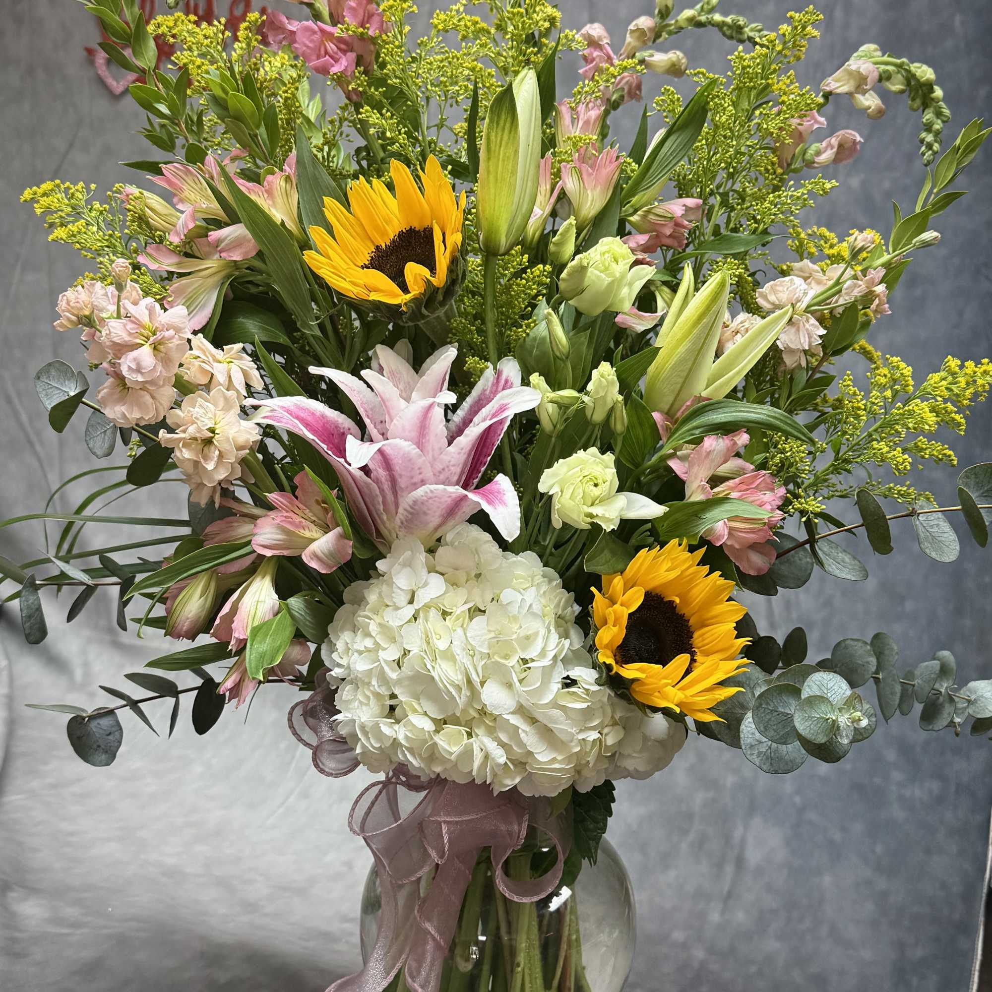 Mixed bouquet with sunflowers, lilies, hydrangea, and alstroemeria in a glass vase