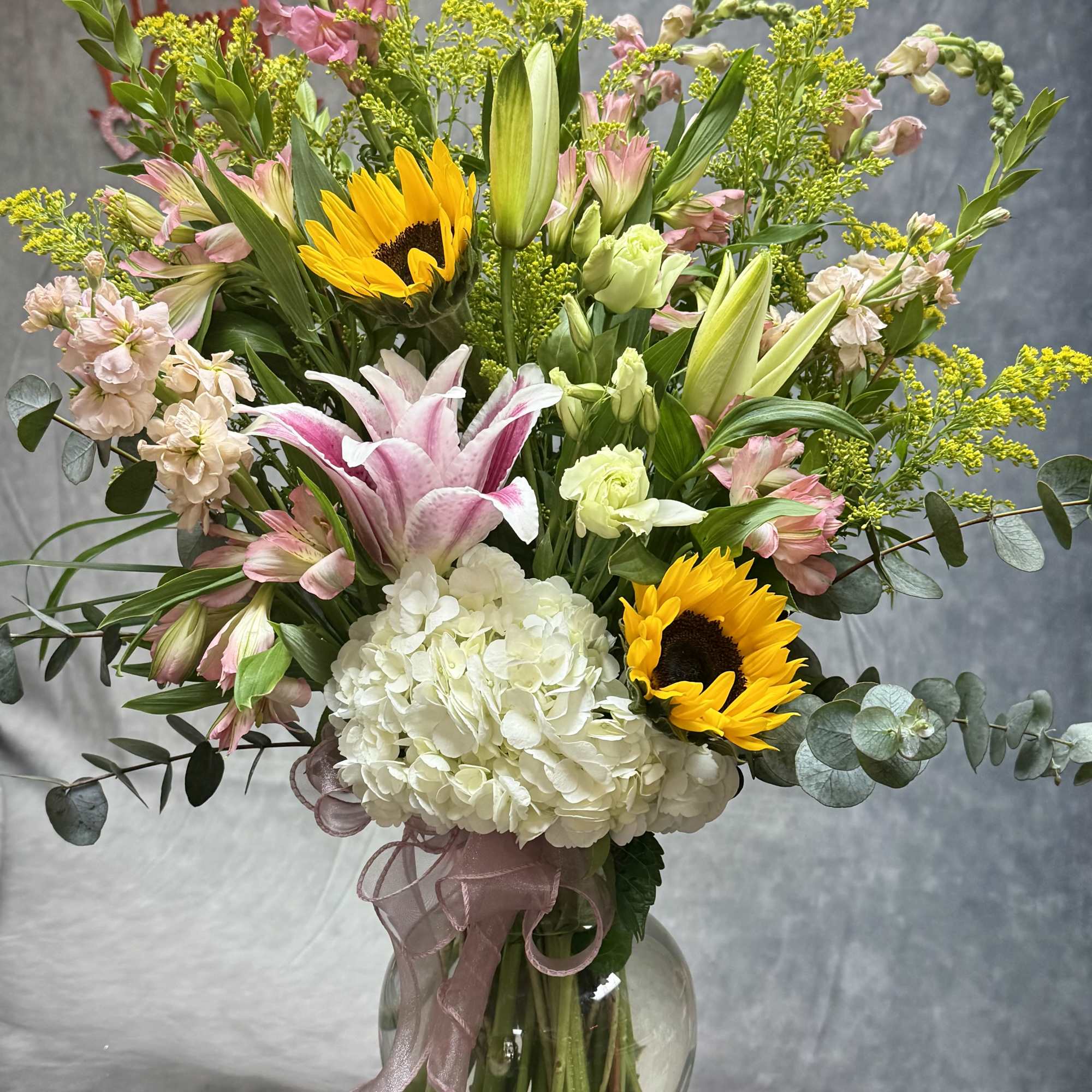 Mixed bouquet in a glass vase with sunflowers, lilies, and hydrangea