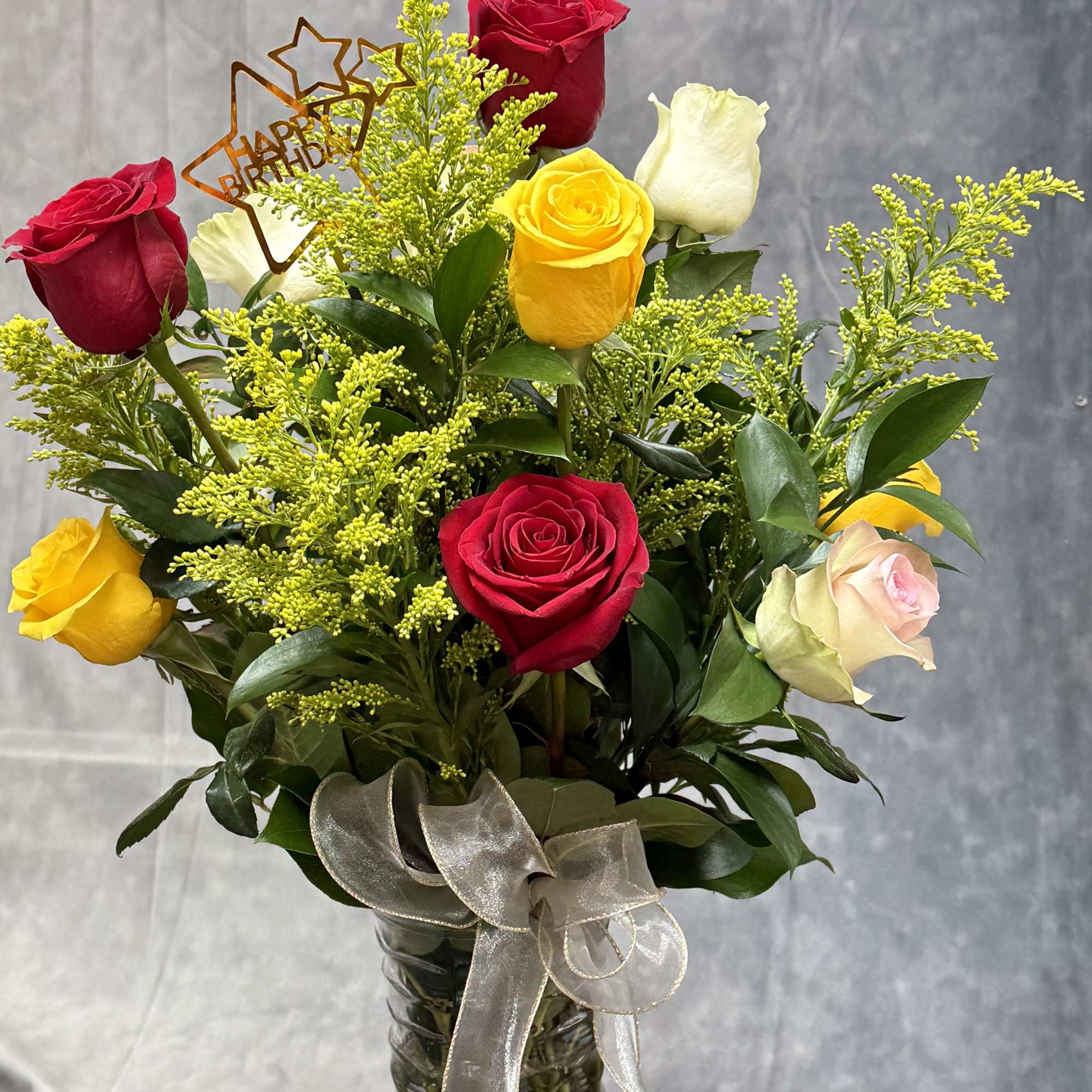 Bouquet of red, yellow, white, and pink roses in a glass vase