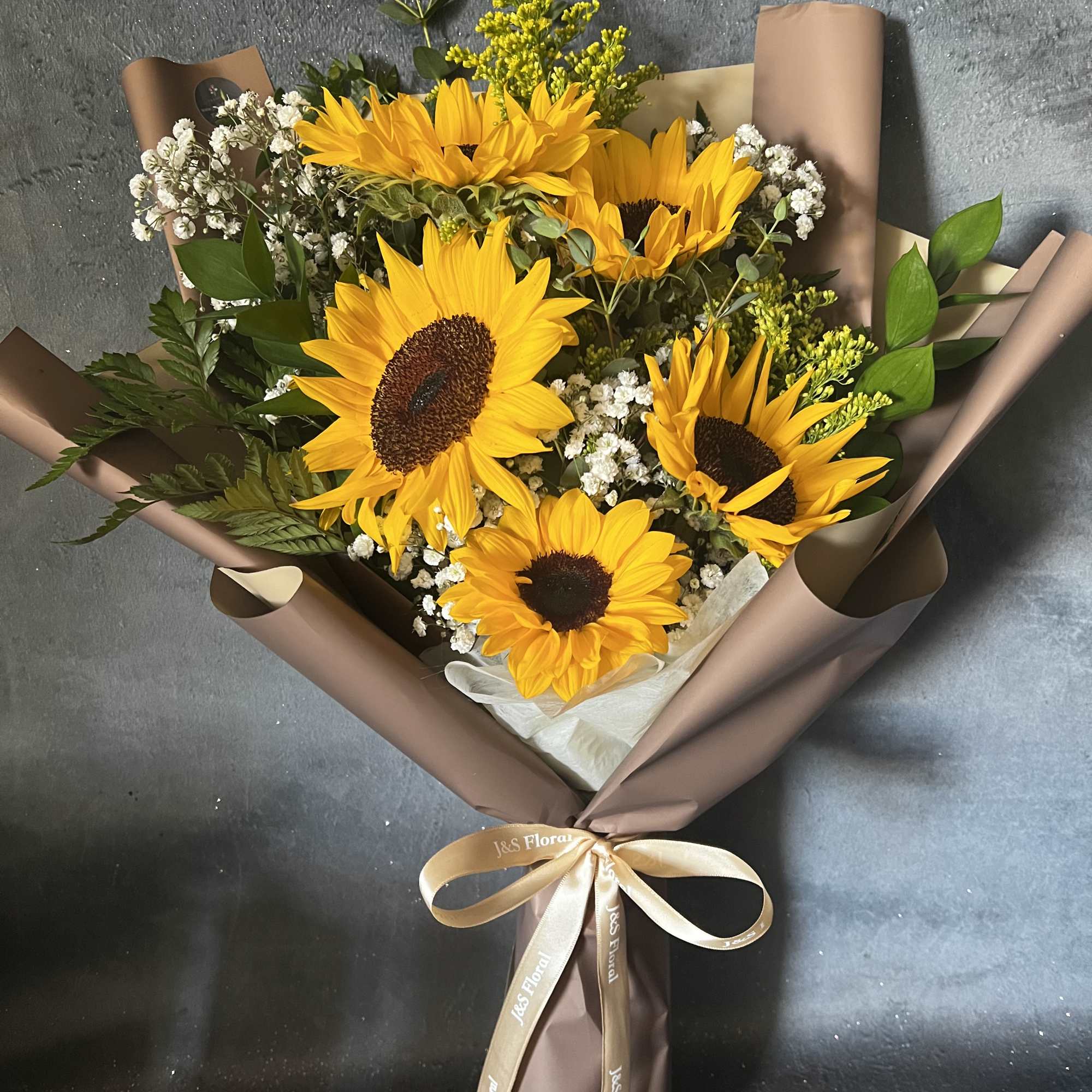 Bouquet of yellow sunflowers wrapped in brown paper with a ribbon