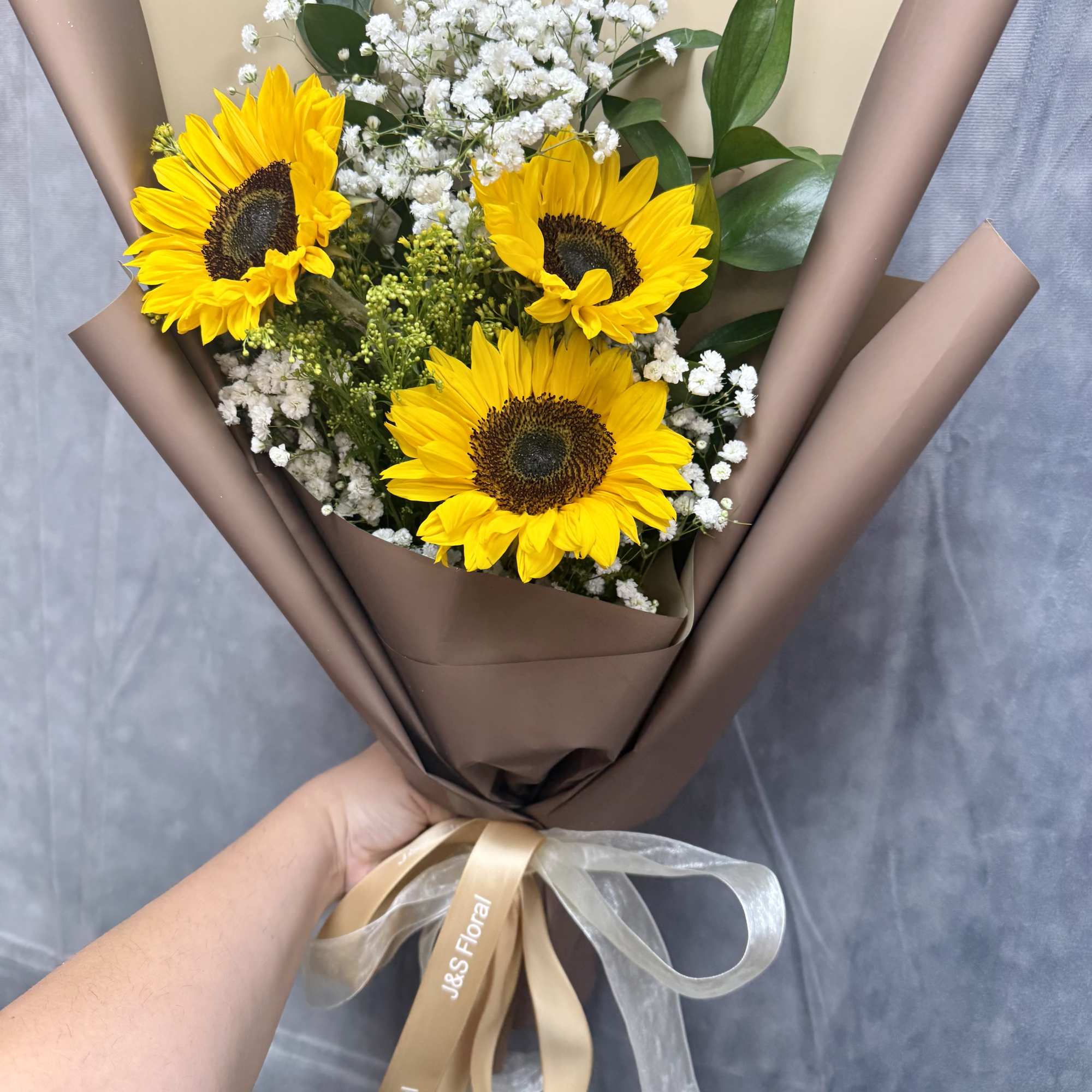Bouquet of sunflowers and white baby's breath wrapped in brown paper