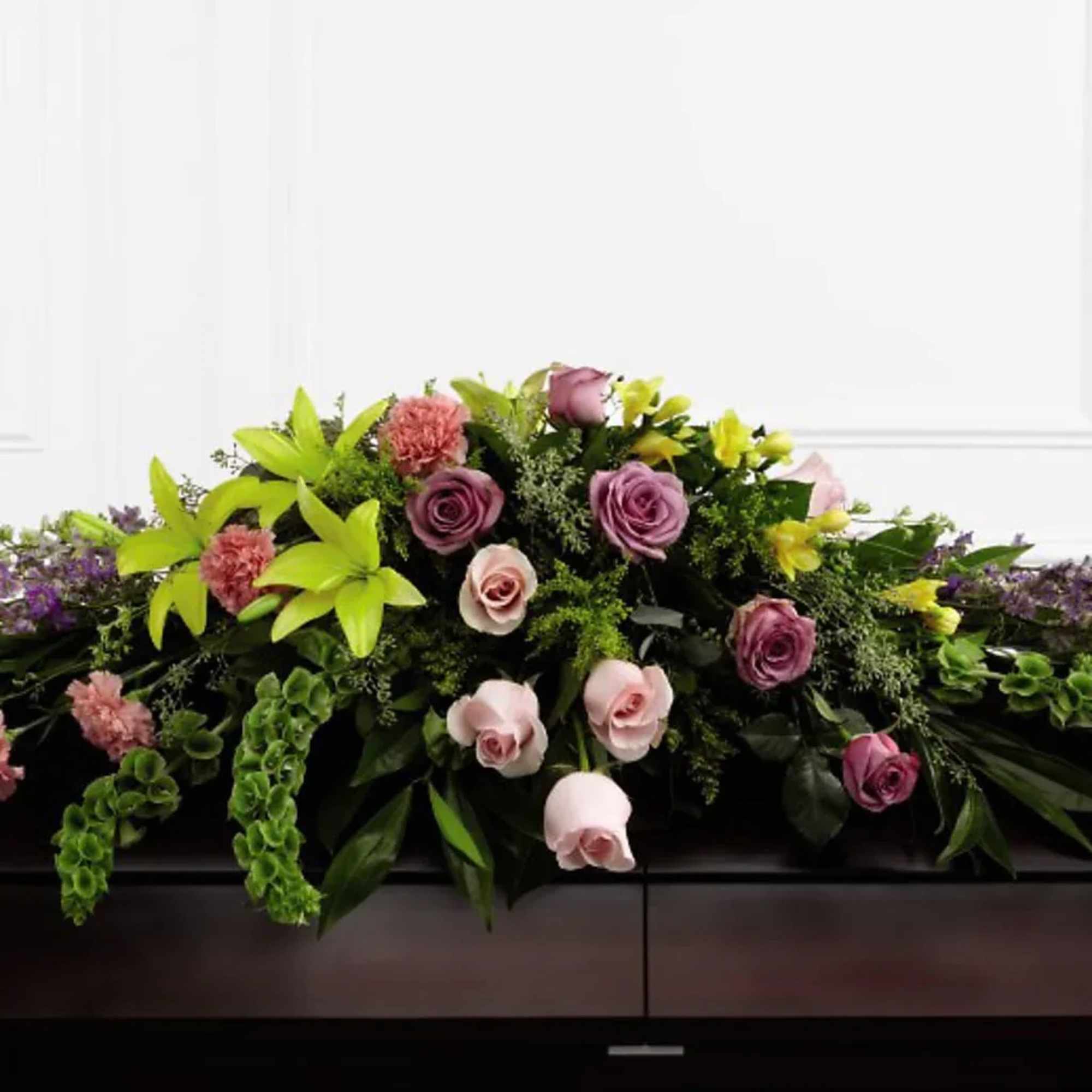 Casket spray with pink and lavender roses and bright green lilies