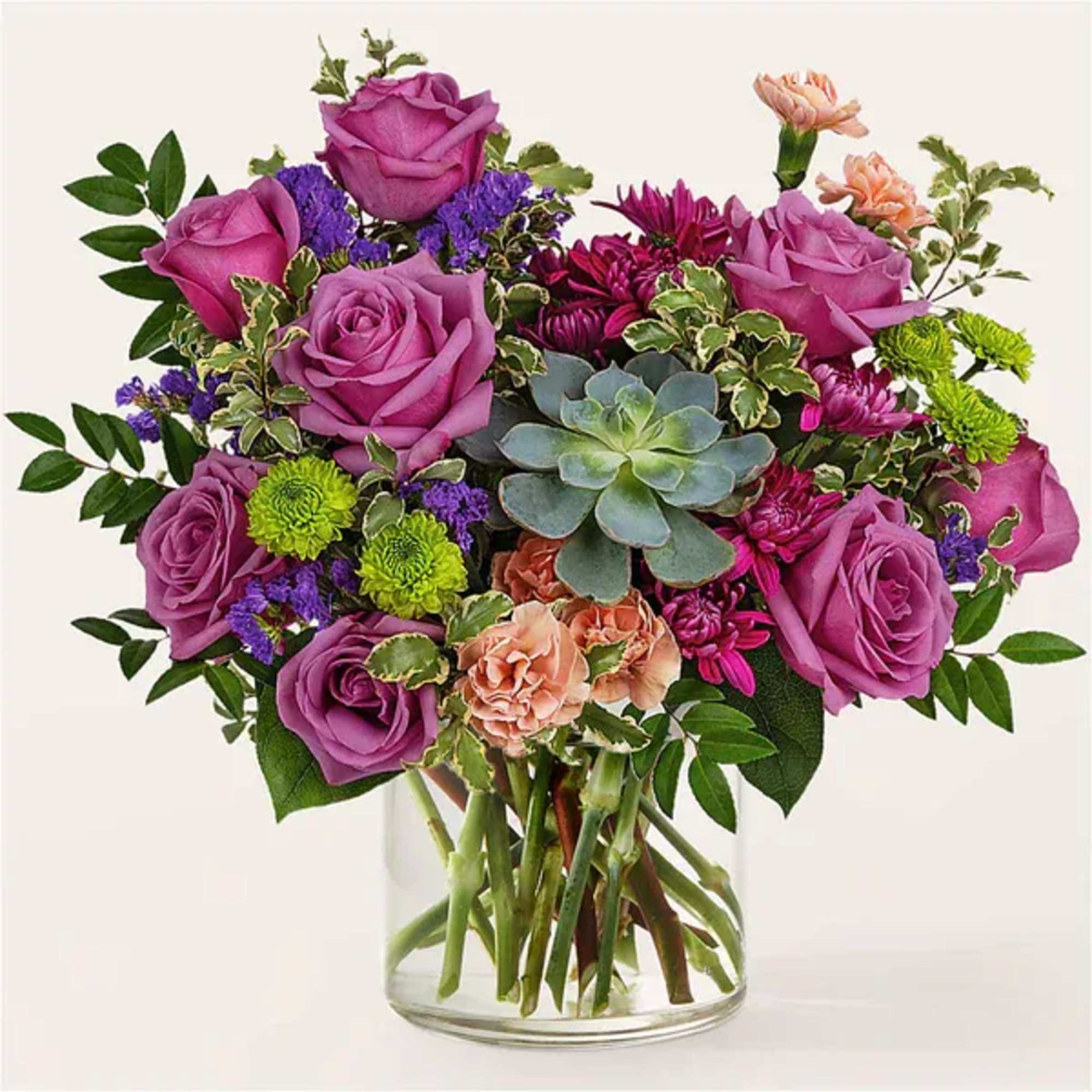 Bouquet of purple roses, green mums, and succulents in a clear glass vase