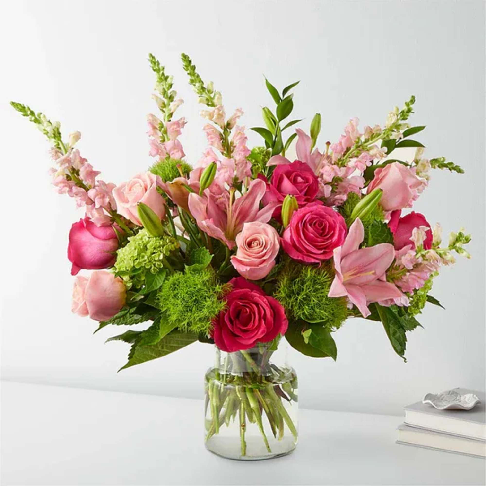 Pink roses and lilies arranged in a clear glass vase