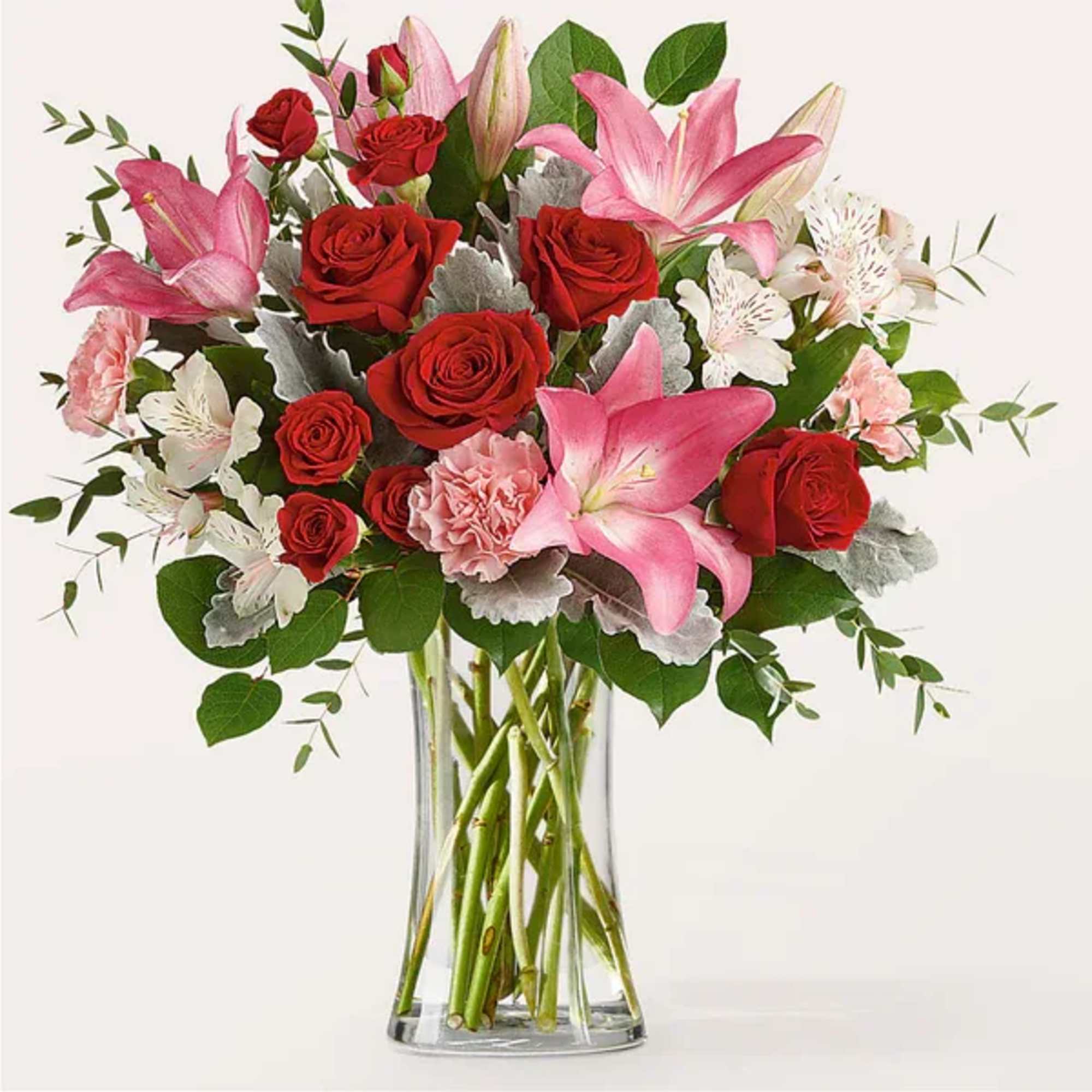 Bouquet of red roses and pink lilies in a clear glass vase