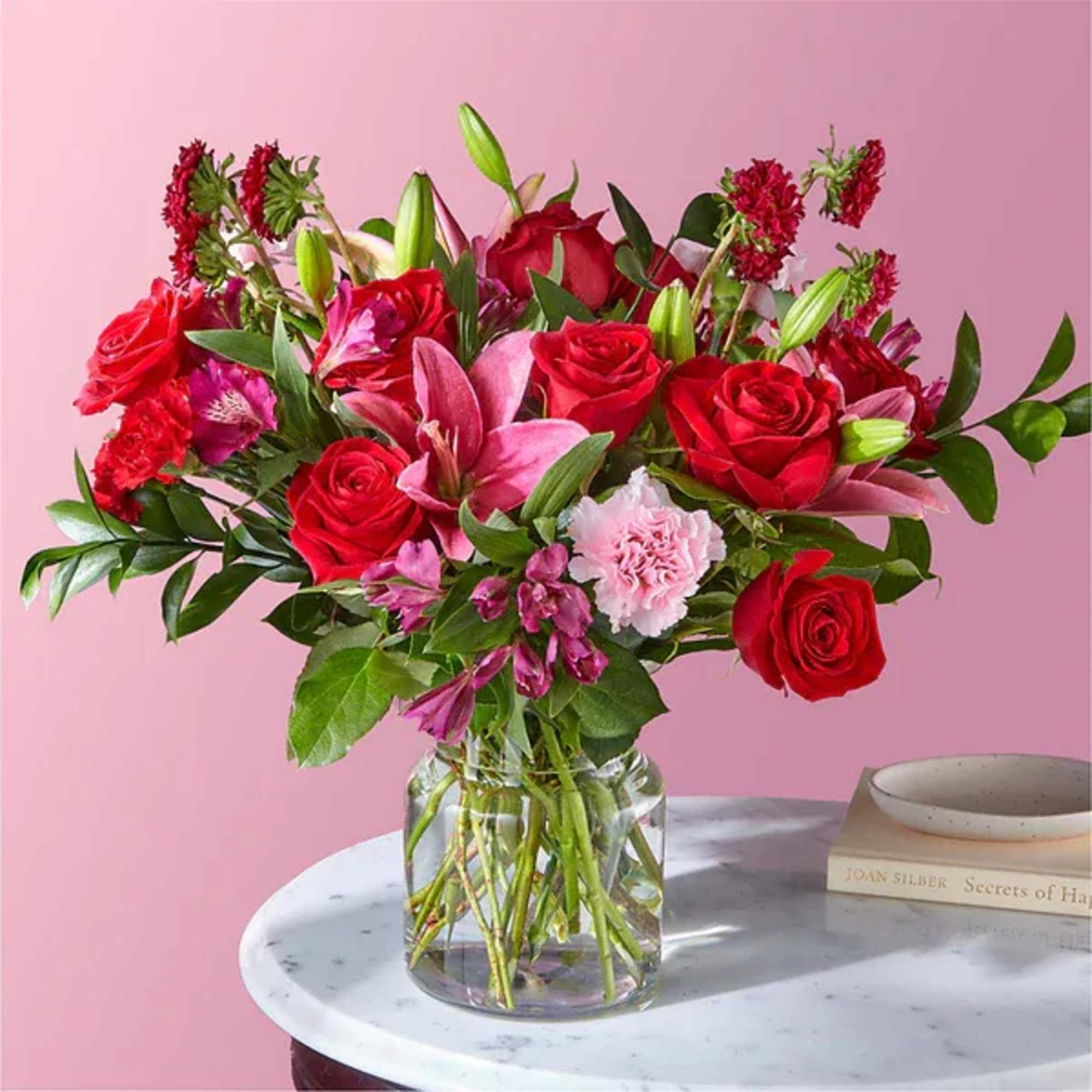 Bouquet of red roses and pink lilies in a clear glass vase