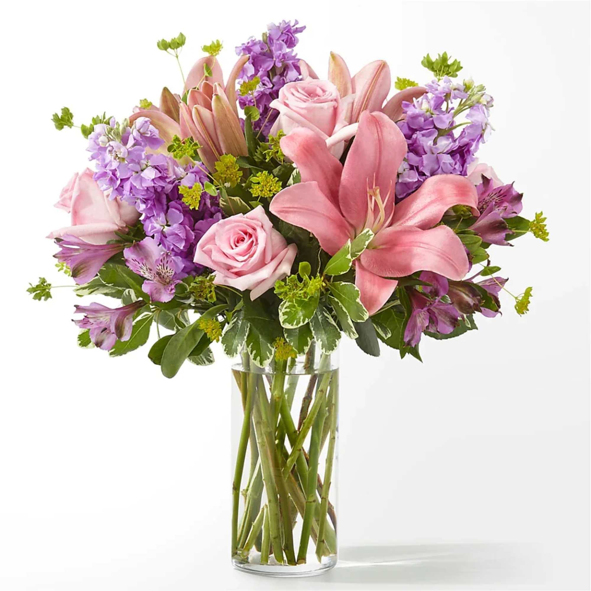 Pink lilies and roses in a clear glass vase with purple flowers