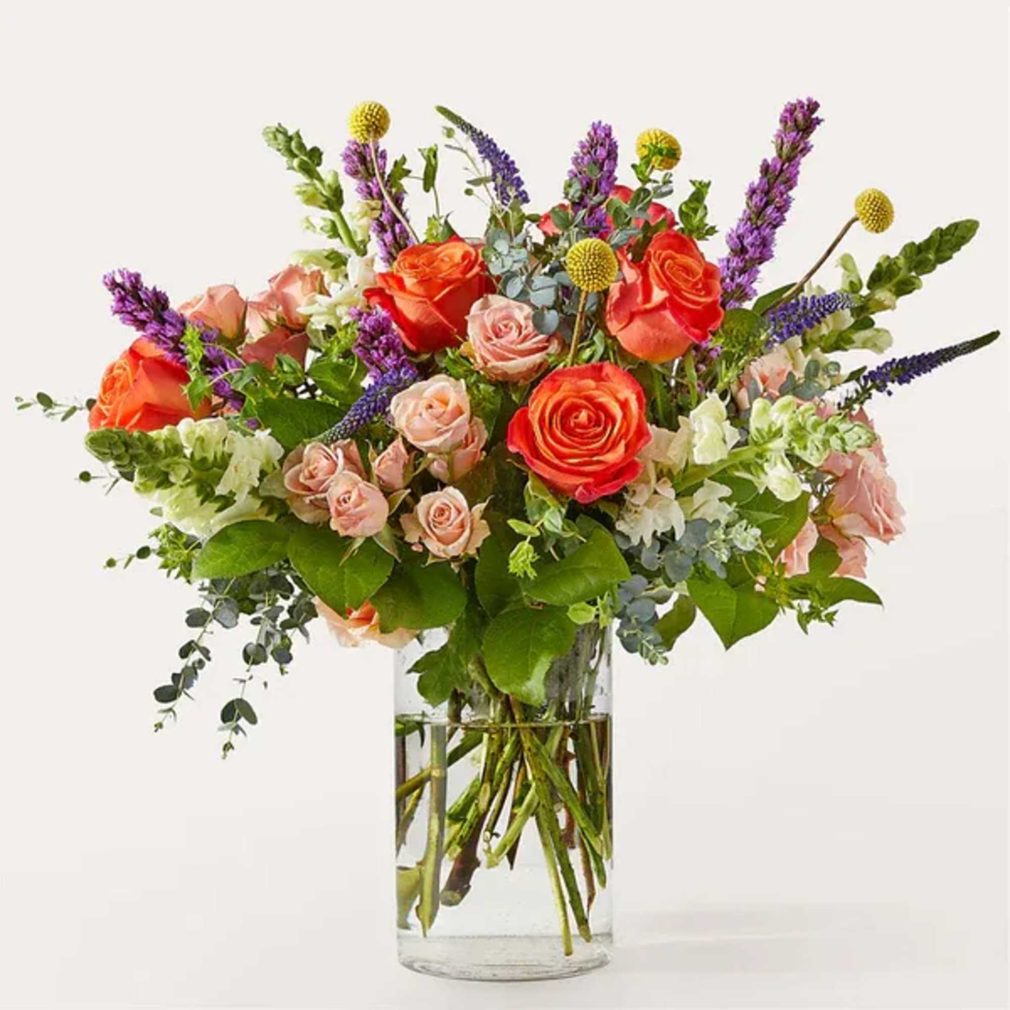 Mixed bouquet of orange and pink roses in a clear glass vase