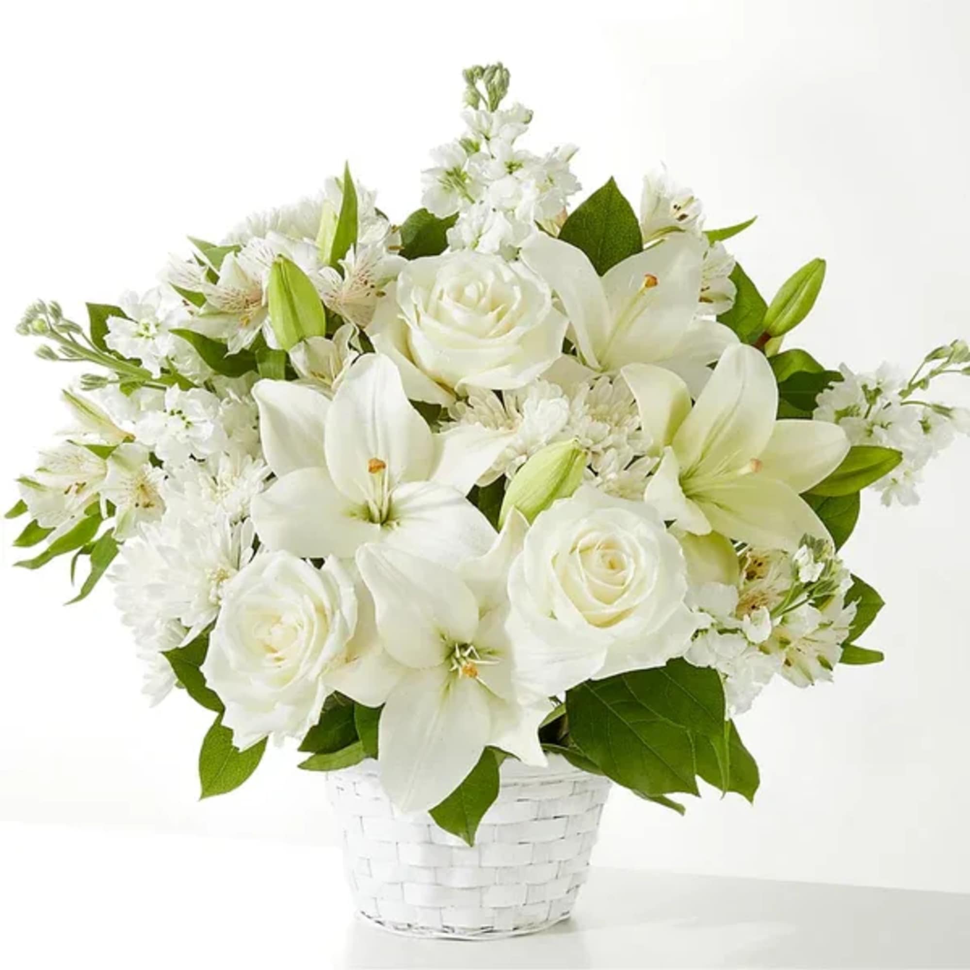 White lilies and roses arranged in a white basket
